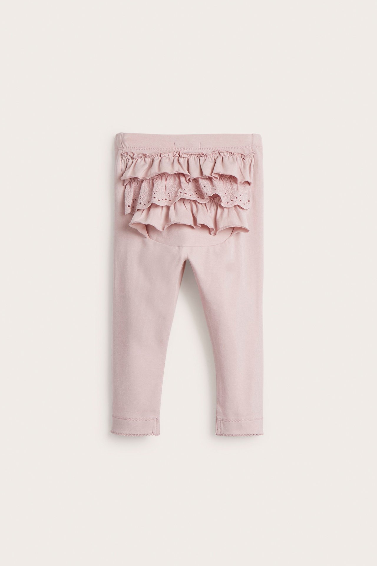 Front view of baby's light pink cotton leggings with ruffles and eyelet lace detail on the back.