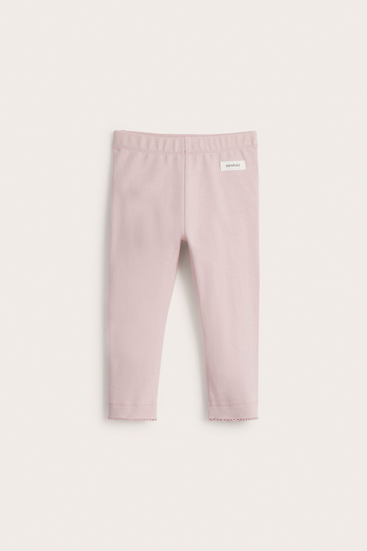 Front view of baby's light pink cotton leggings with an elastic waist and picot trim at the ankles.