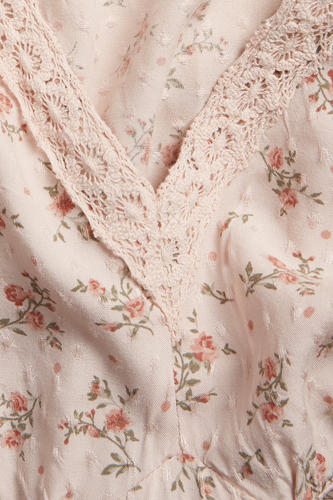 Close-up of a light pink floral viscose dress with a lace-trimmed V-neckline.