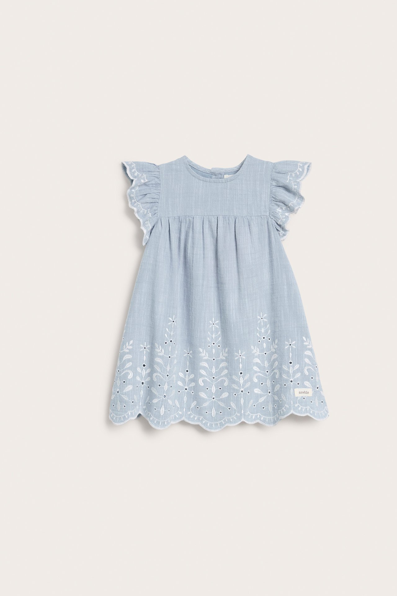 Front view of a light blue chambray kid's dress with white embroidery, ruffled sleeves, and back buttons.