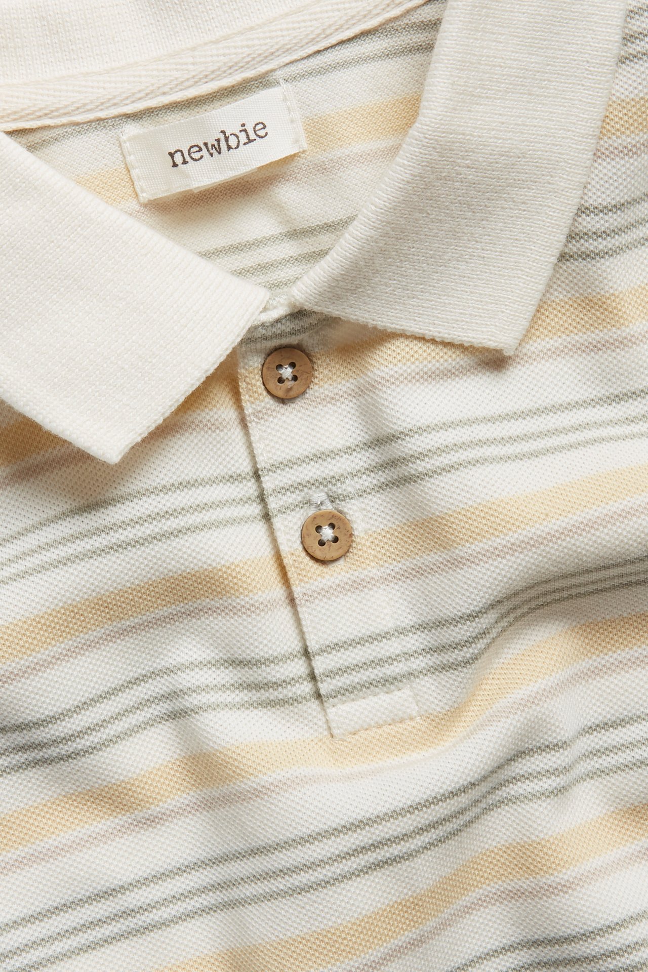 Close-up of an off-white striped cotton polo t-shirt with a collar and two wooden buttons.