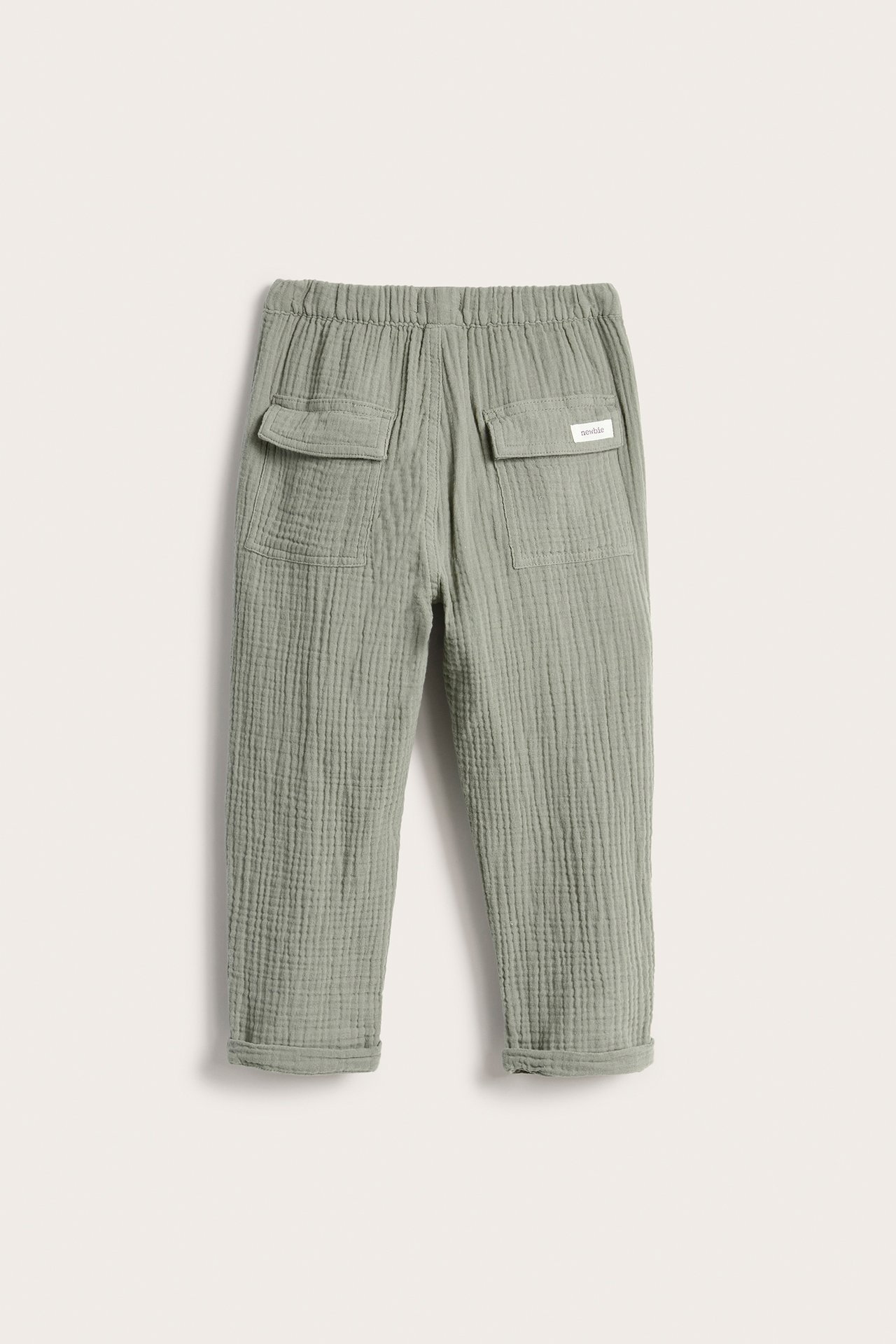 Back view of kid's green woven cotton trousers with elastic waist, two flap back pockets, rolled cuffs.