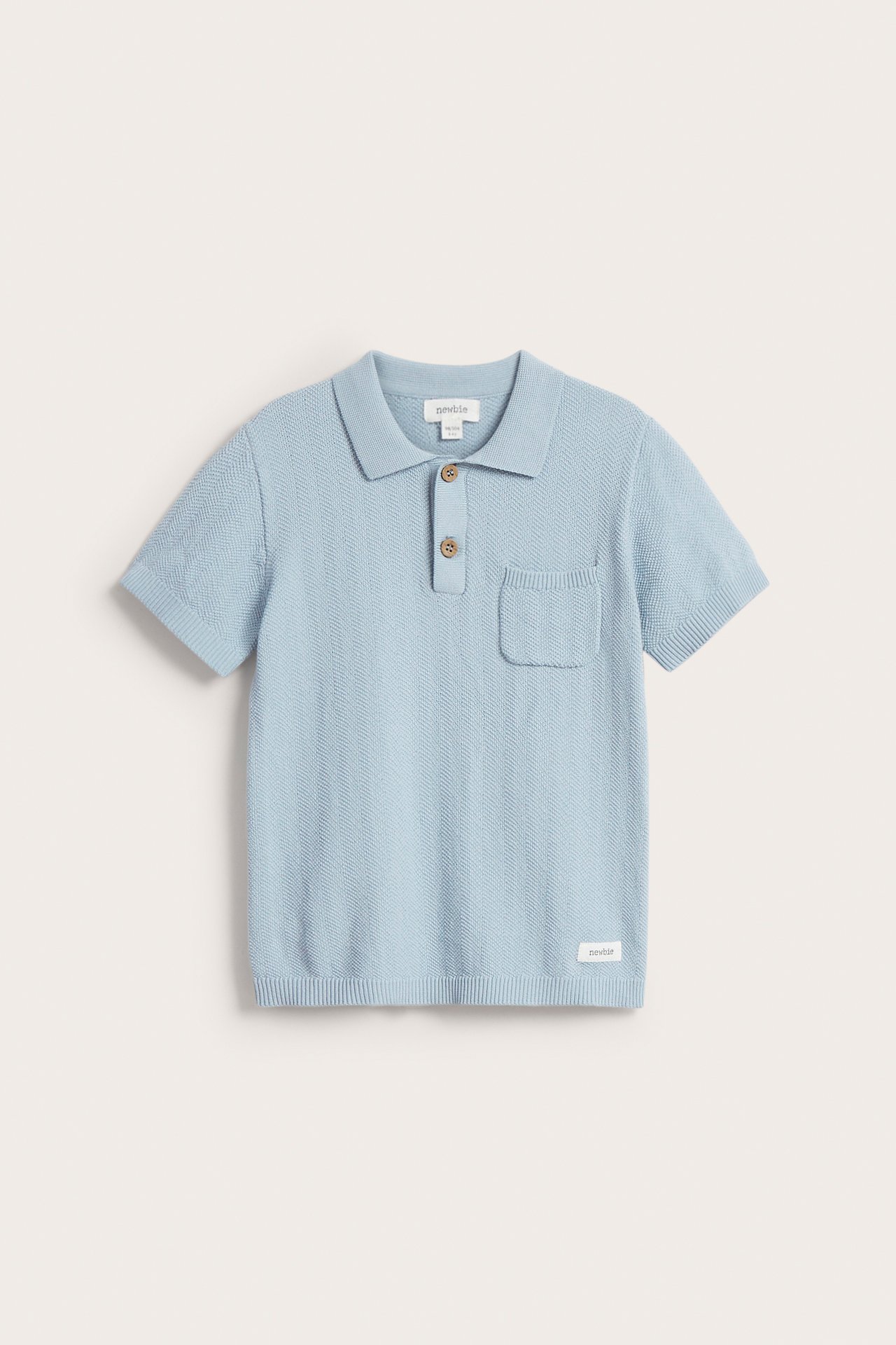 Front view: Light blue knitted kid's polo shirt, collar, two buttons, short sleeves, chest pocket.