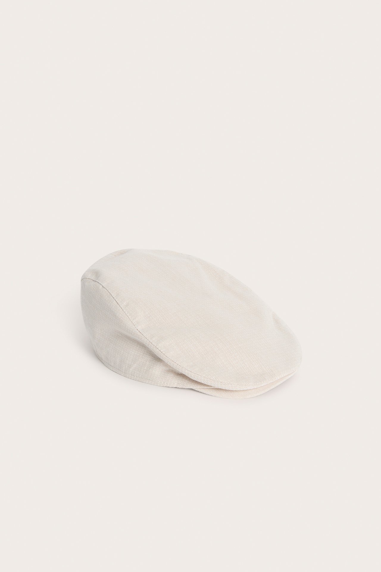 Side view of a solid beige structured woven flat cap for kids.