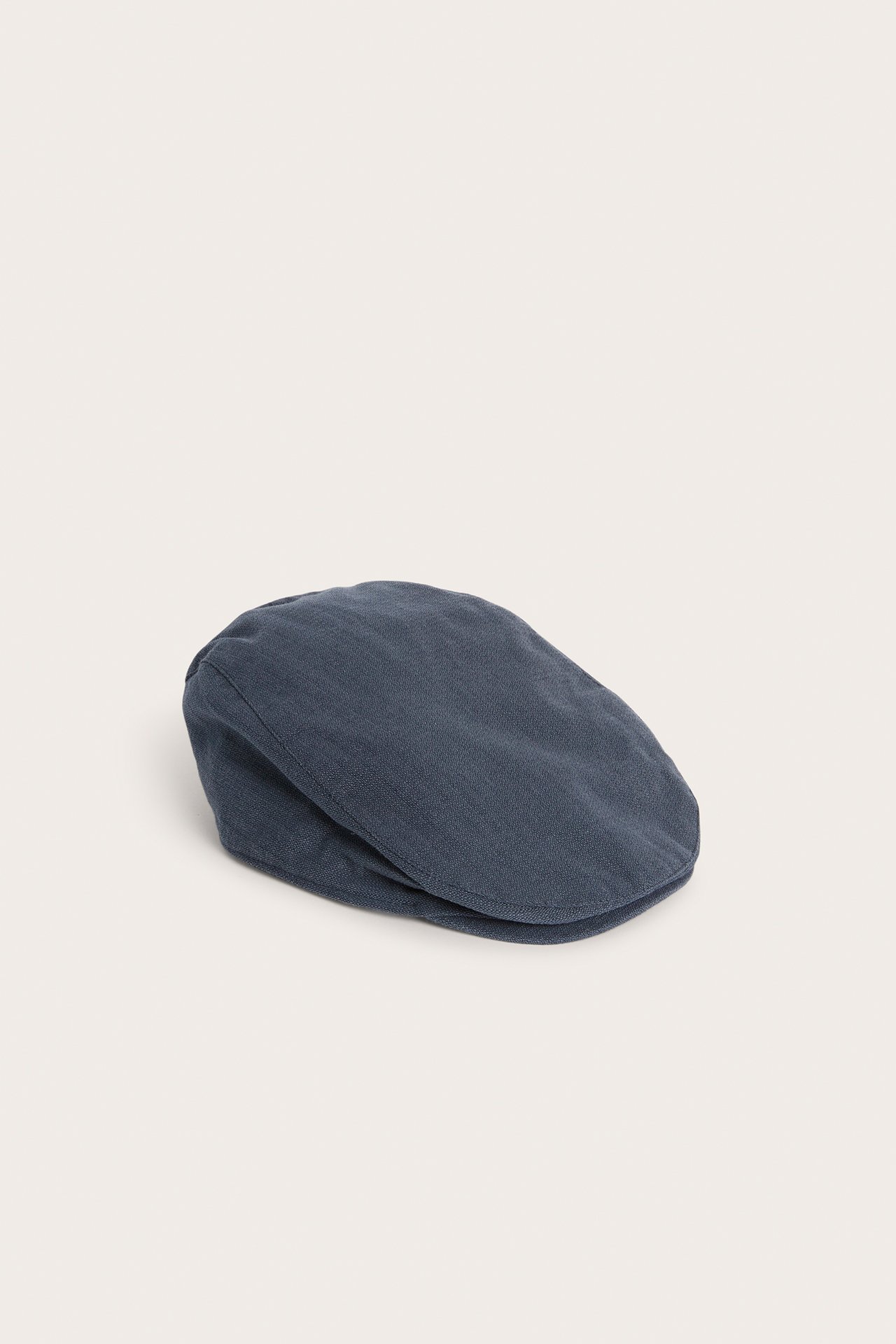 Side view of a dark blue solid-colored structured flat cap.
