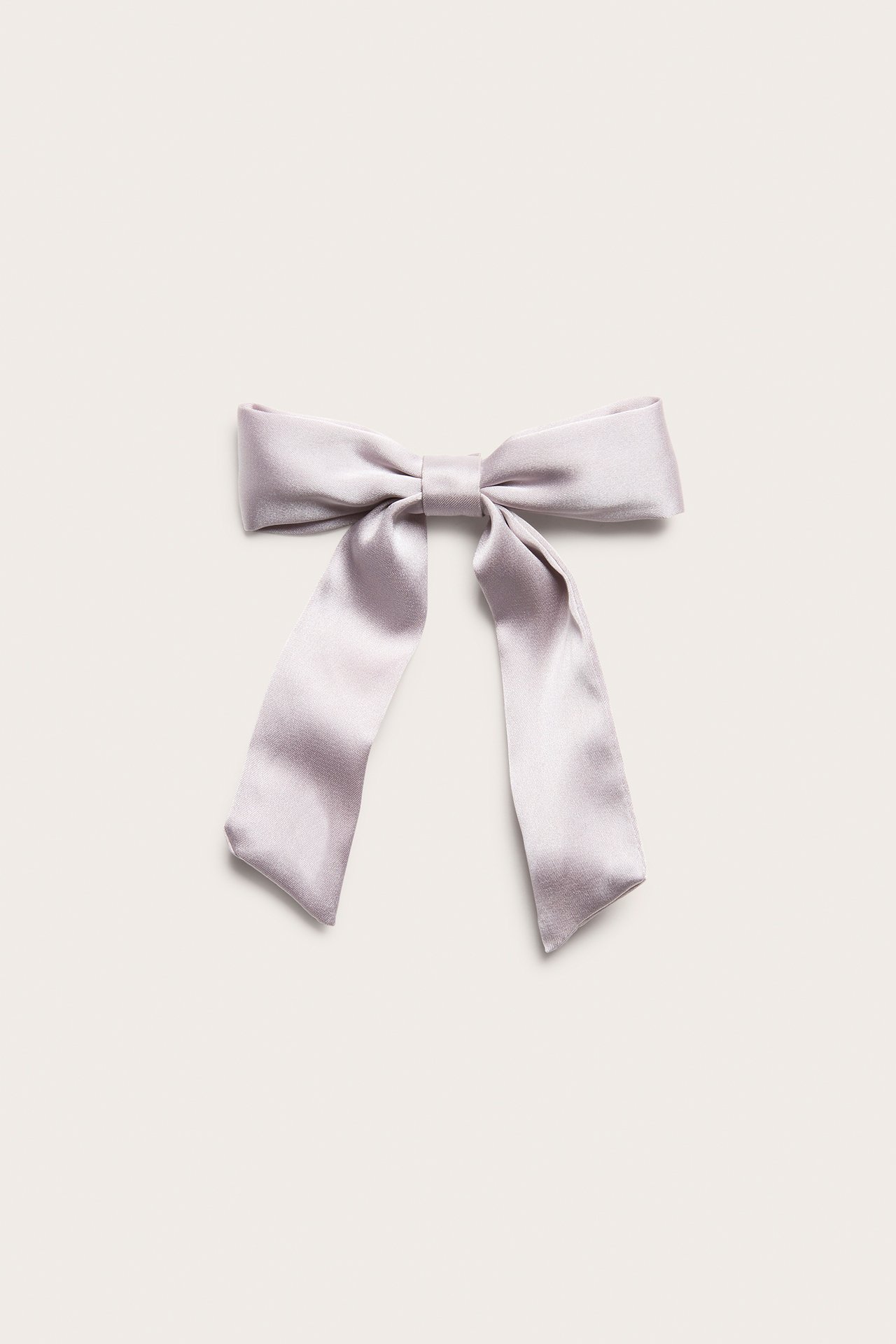 Close-up front view of a light lilac satin bow hair clip with a metal fastening.