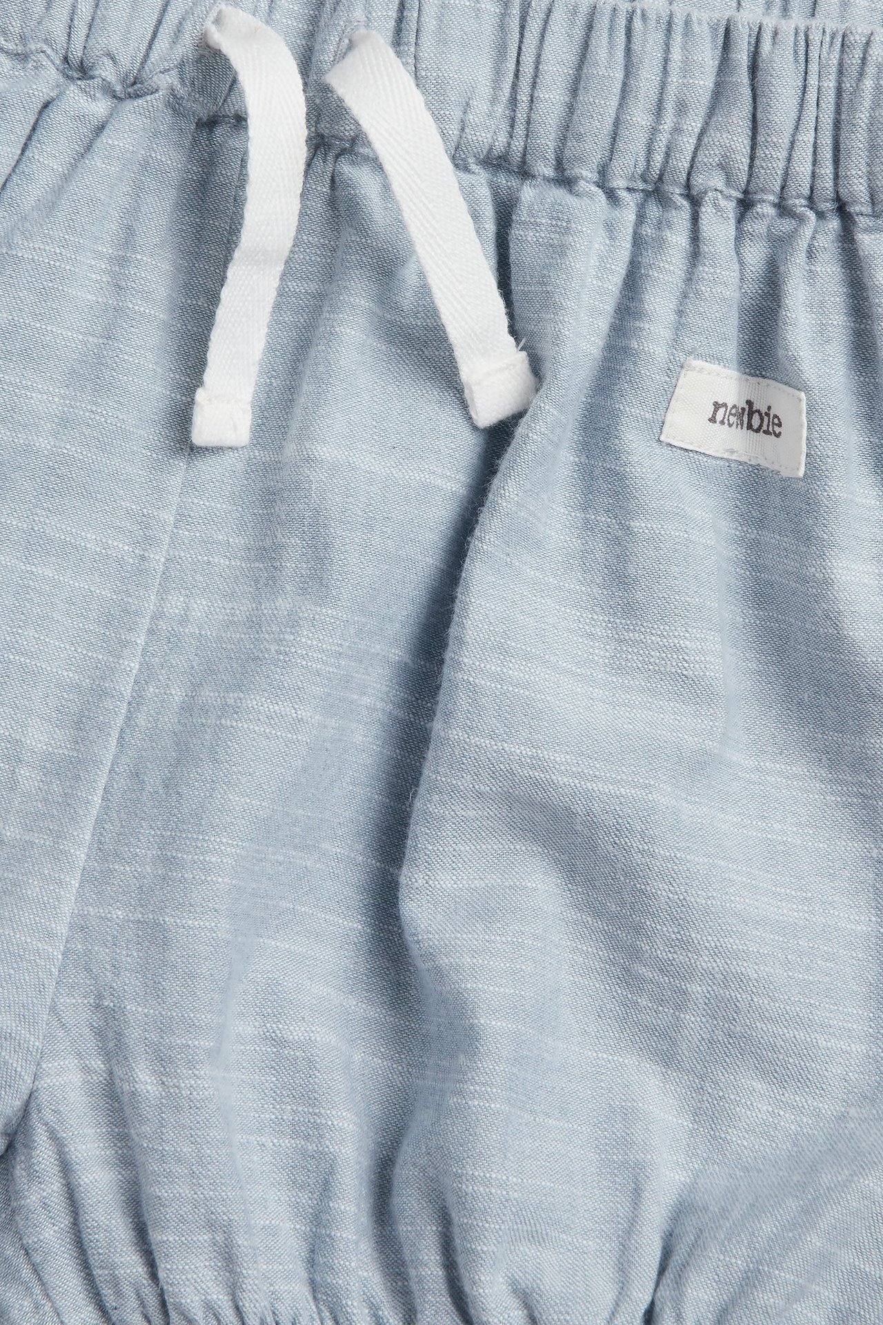 Nahaufnahme blauer Chambray-Shorts mit elastischem Bund und weißem Kordelzug.