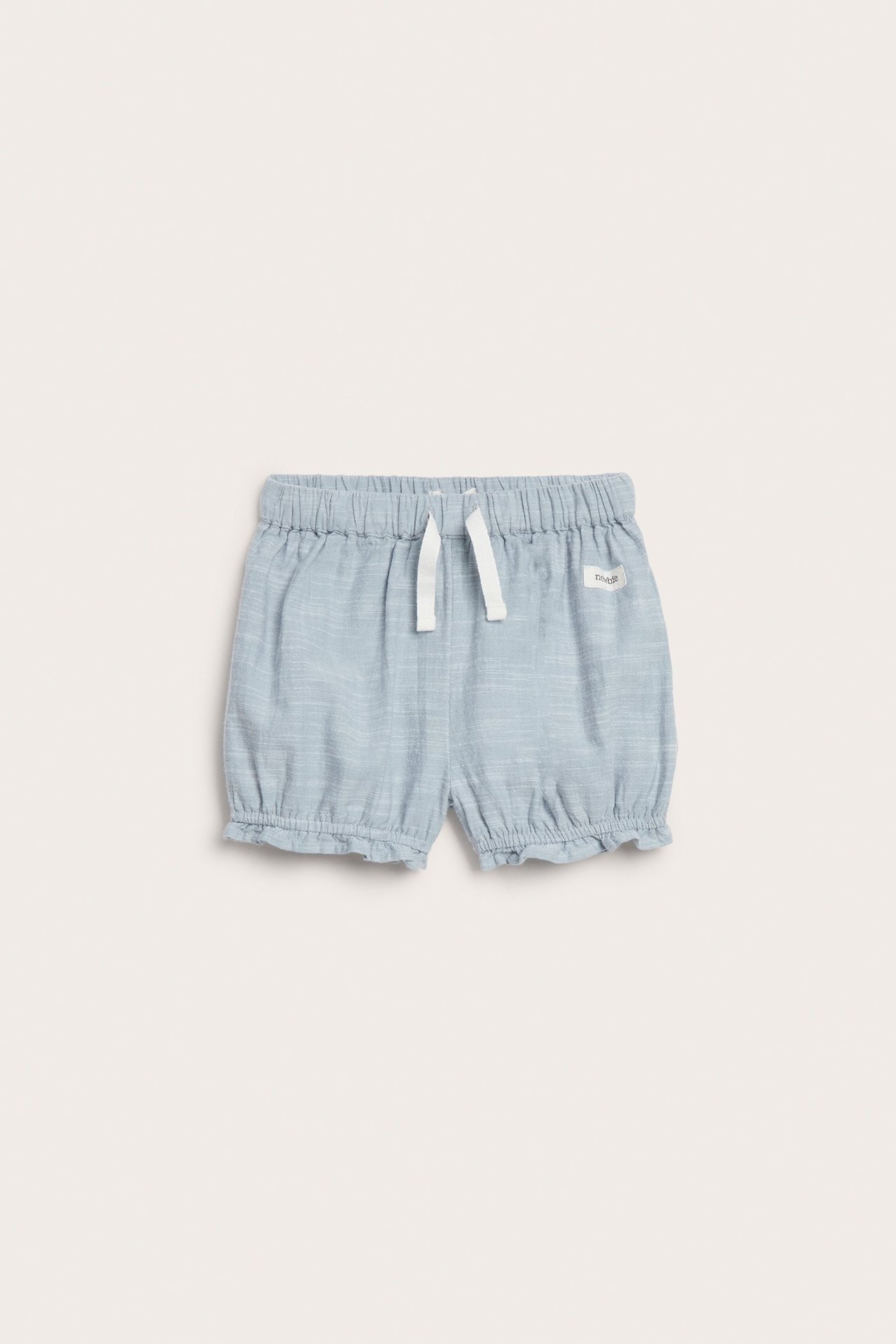 Vorderansicht von hellblauen Chambray-Kindershorts mit elastischem Bund, weißem Kordelzug und Rüschen an den Beinabschlüssen.