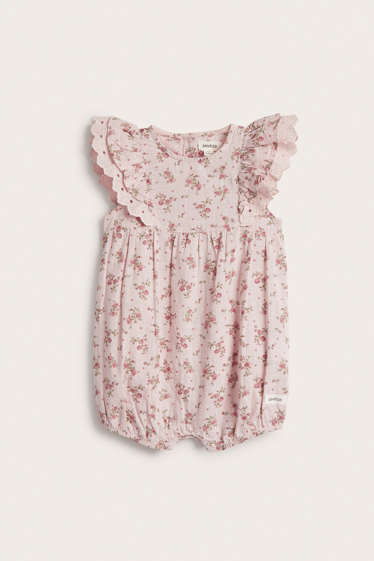 Front view of a light pink cotton baby playsuit with small floral print, ruffle sleeves, and snap fasteners.