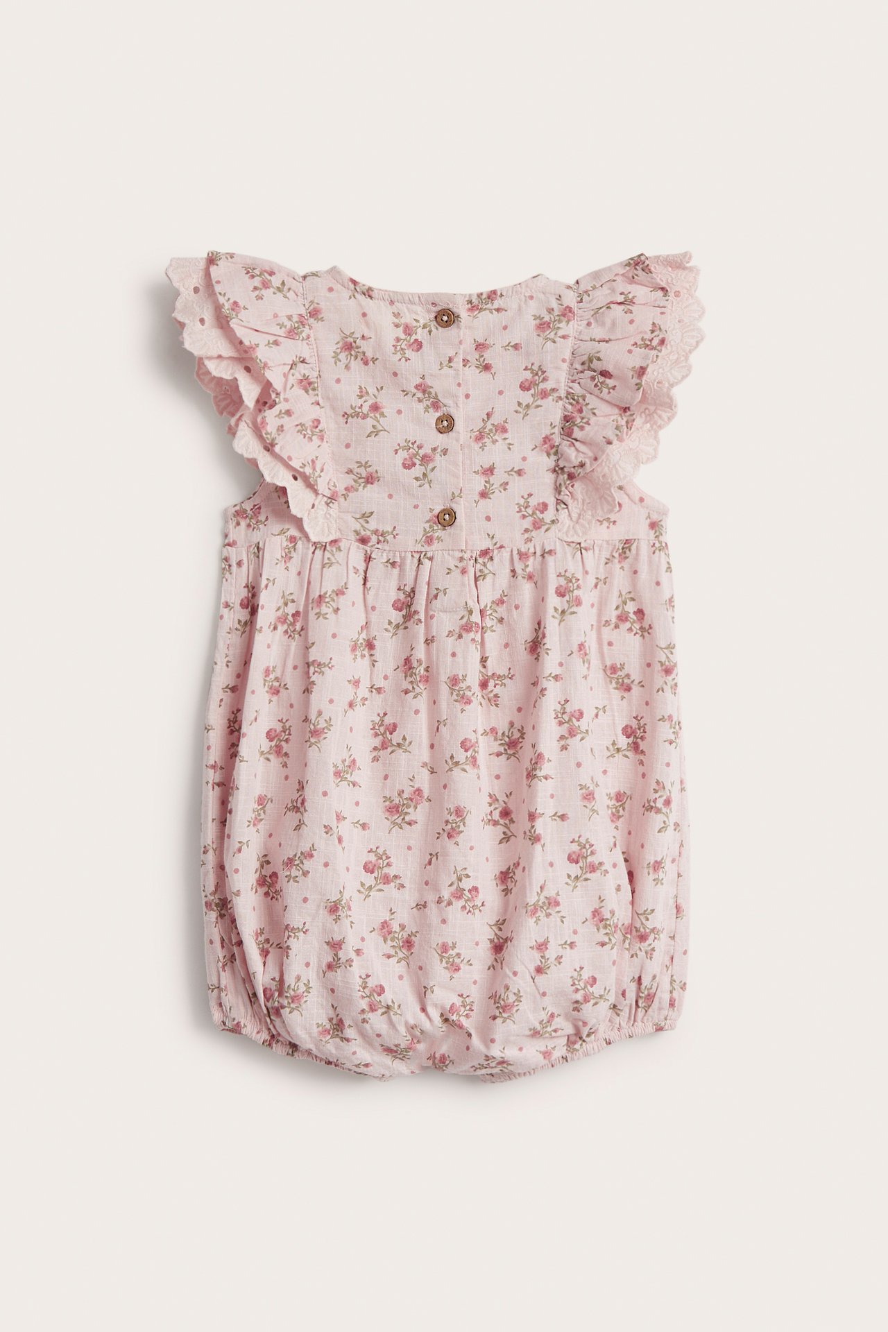 Back view of a baby's light pink floral cotton playsuit with ruffle lace sleeves and back buttons.