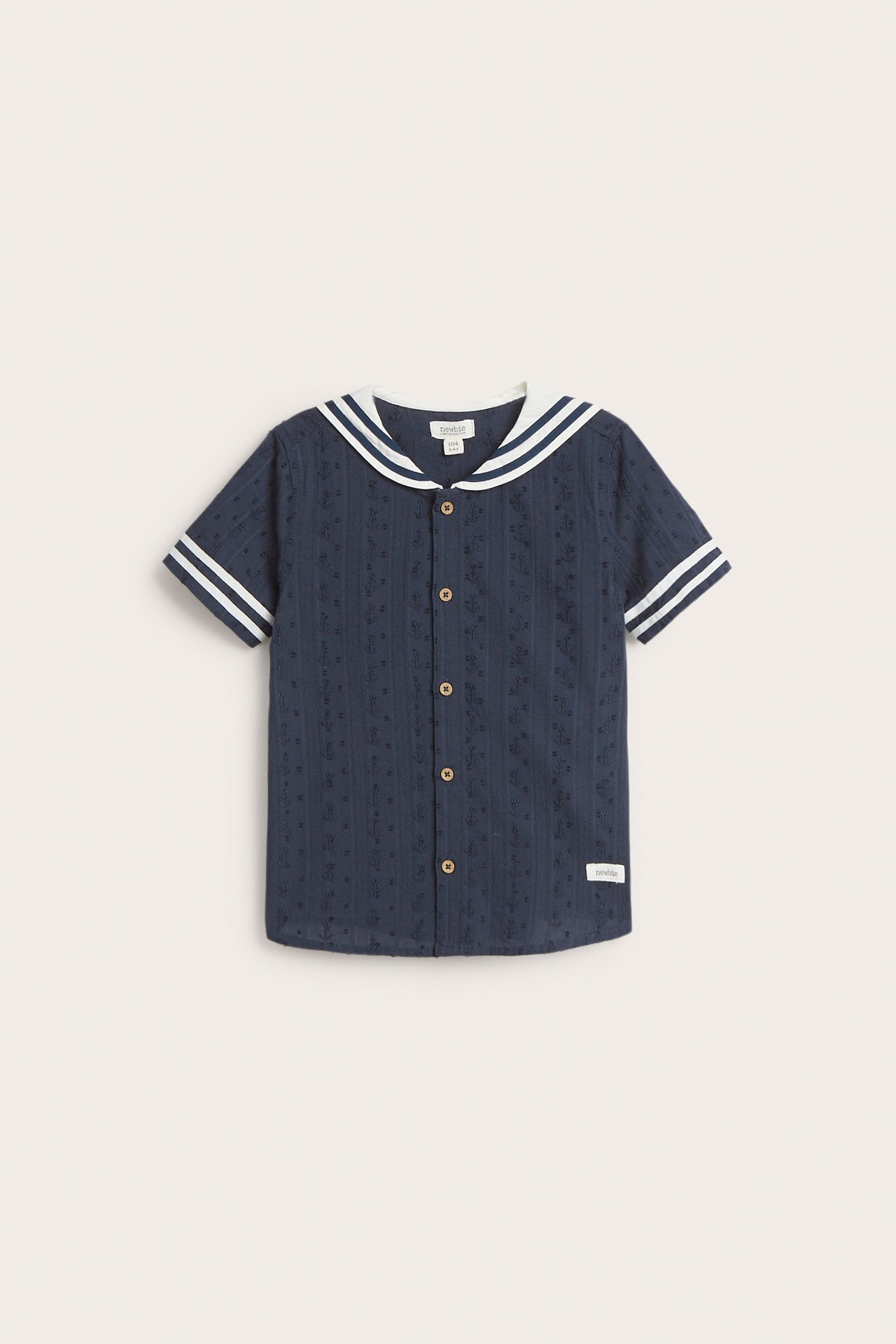Front view: Kid's dark blue patterned cotton short-sleeved shirt with white striped sailor collar and front buttons.