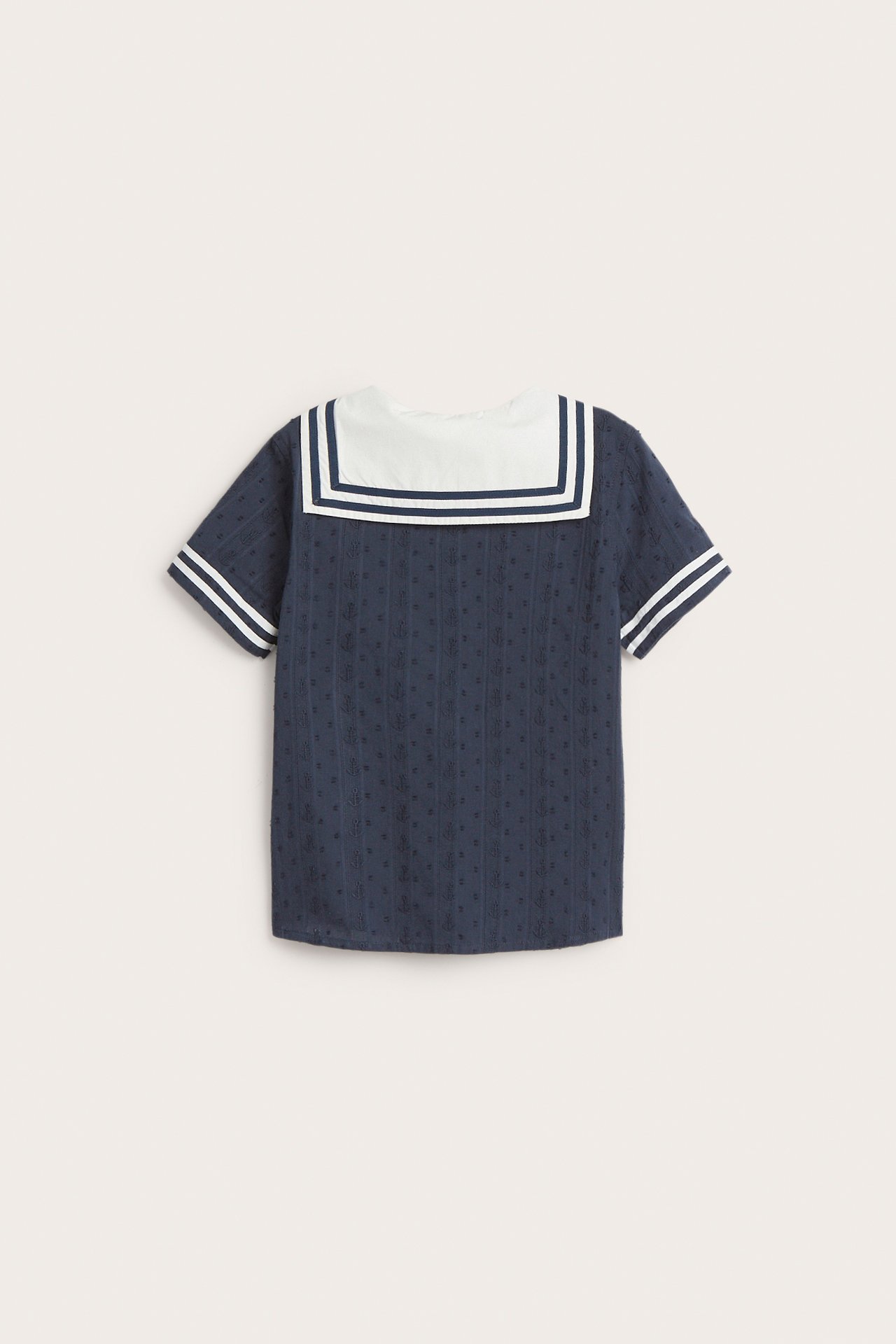 Back view of a kid's dark blue short-sleeved shirt with white sailor collar and striped cuffs.