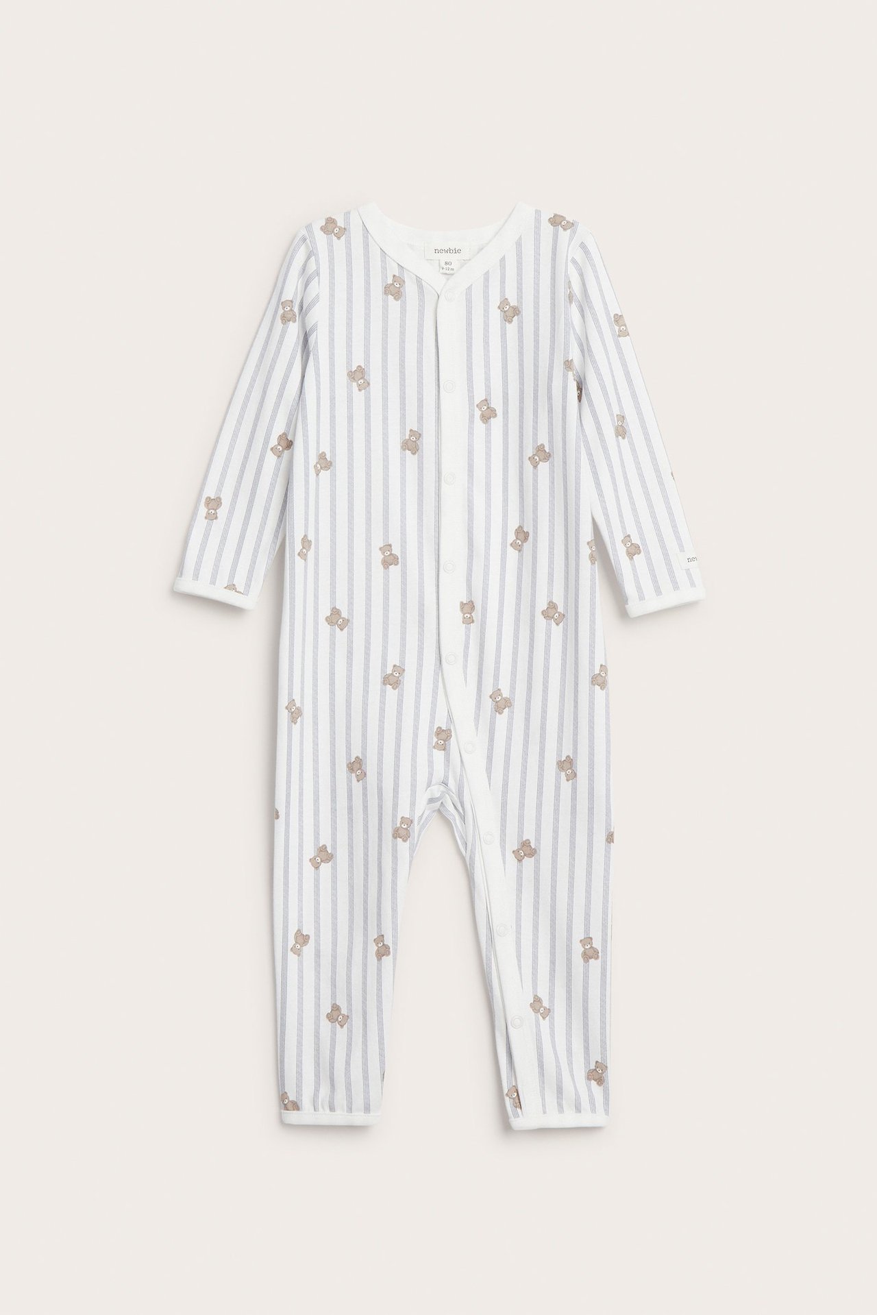 Vorderansicht eines baby-Overall aus gestreifter, cremefarbener Baumwolle mit Teddybär-Print und Druckknöpfen.
