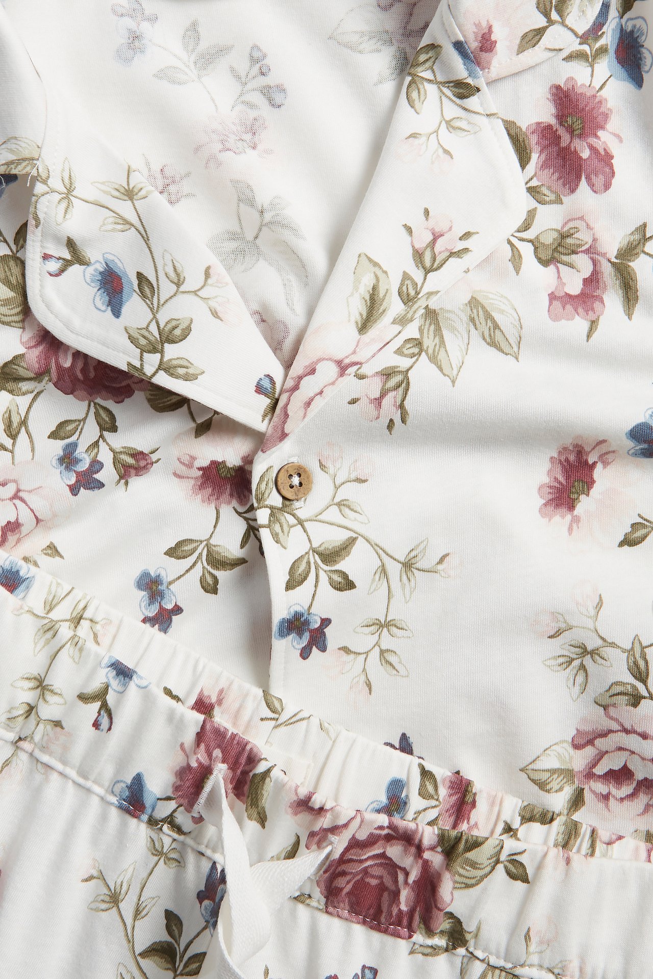 Close-up of white cotton floral pyjamas featuring a buttoned top and drawstring shorts.