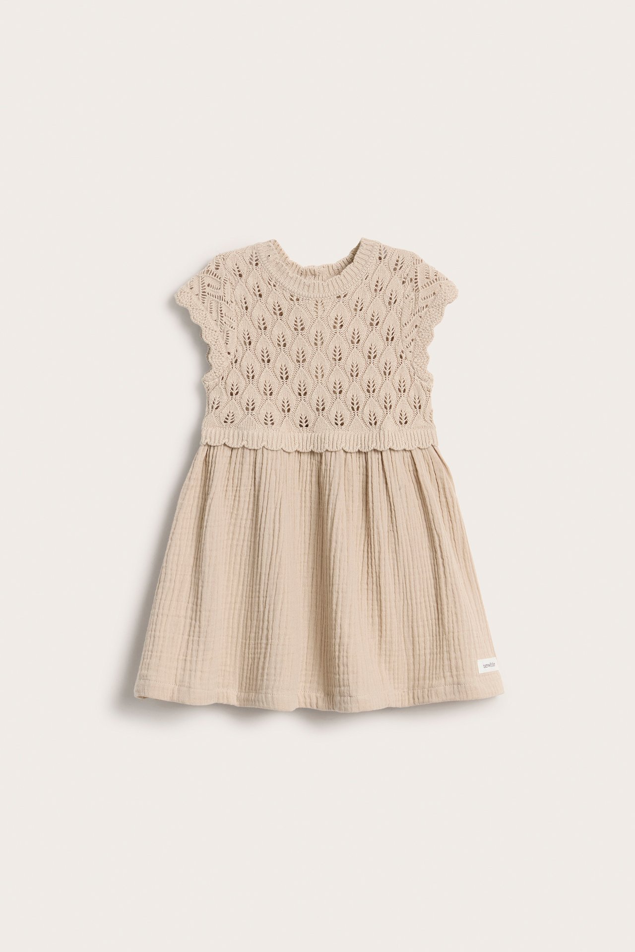 Vorderansicht eines beigen Babykleides mit gestricktem Blattmuster-Oberteil und gerafftem Musselinrock.