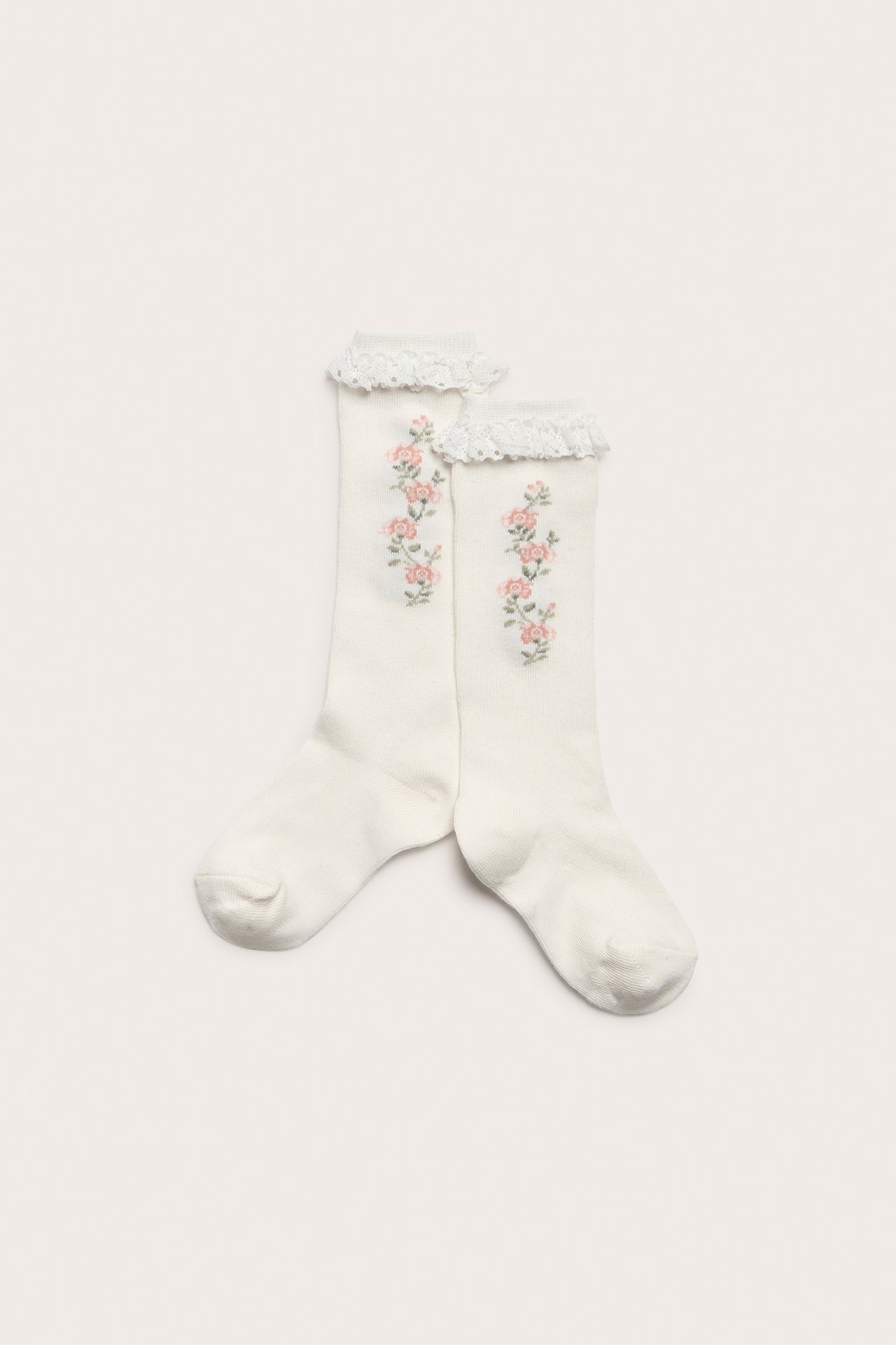 Top-down view of two off-white knee socks with pink floral embroidery and ruffled lace trim at the top.