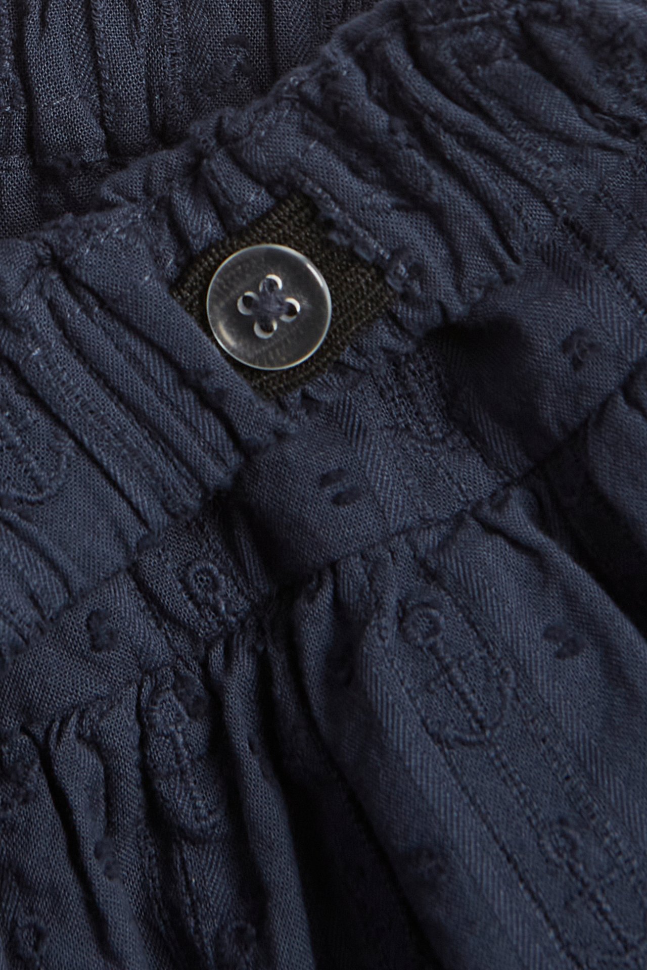 Close-up of a dark blue cotton skort with an adjustable elastic waistband and embroidered anchors.