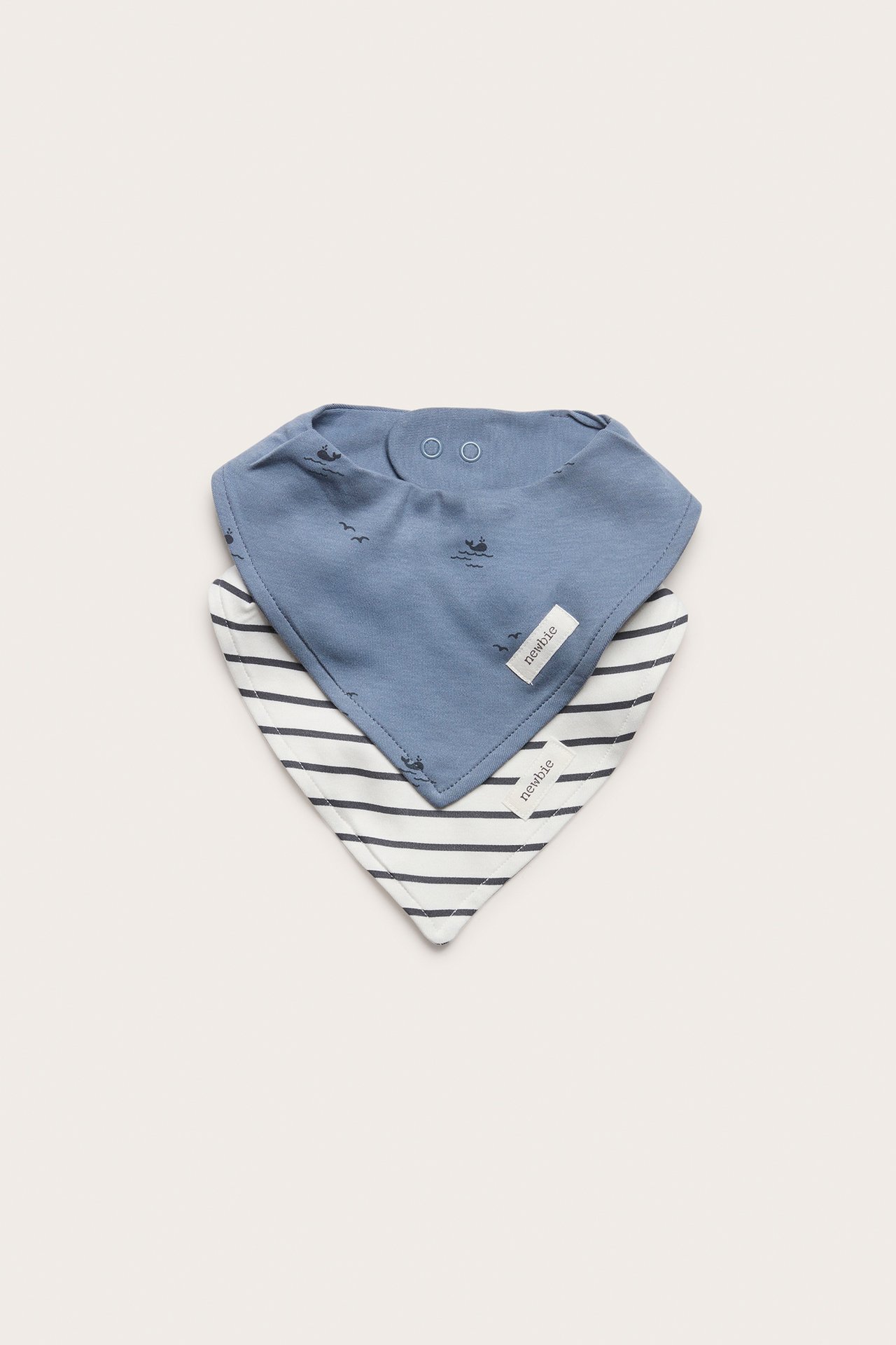 Front view of two baby cotton bibs: a blue one with marine patterns and a white striped one.