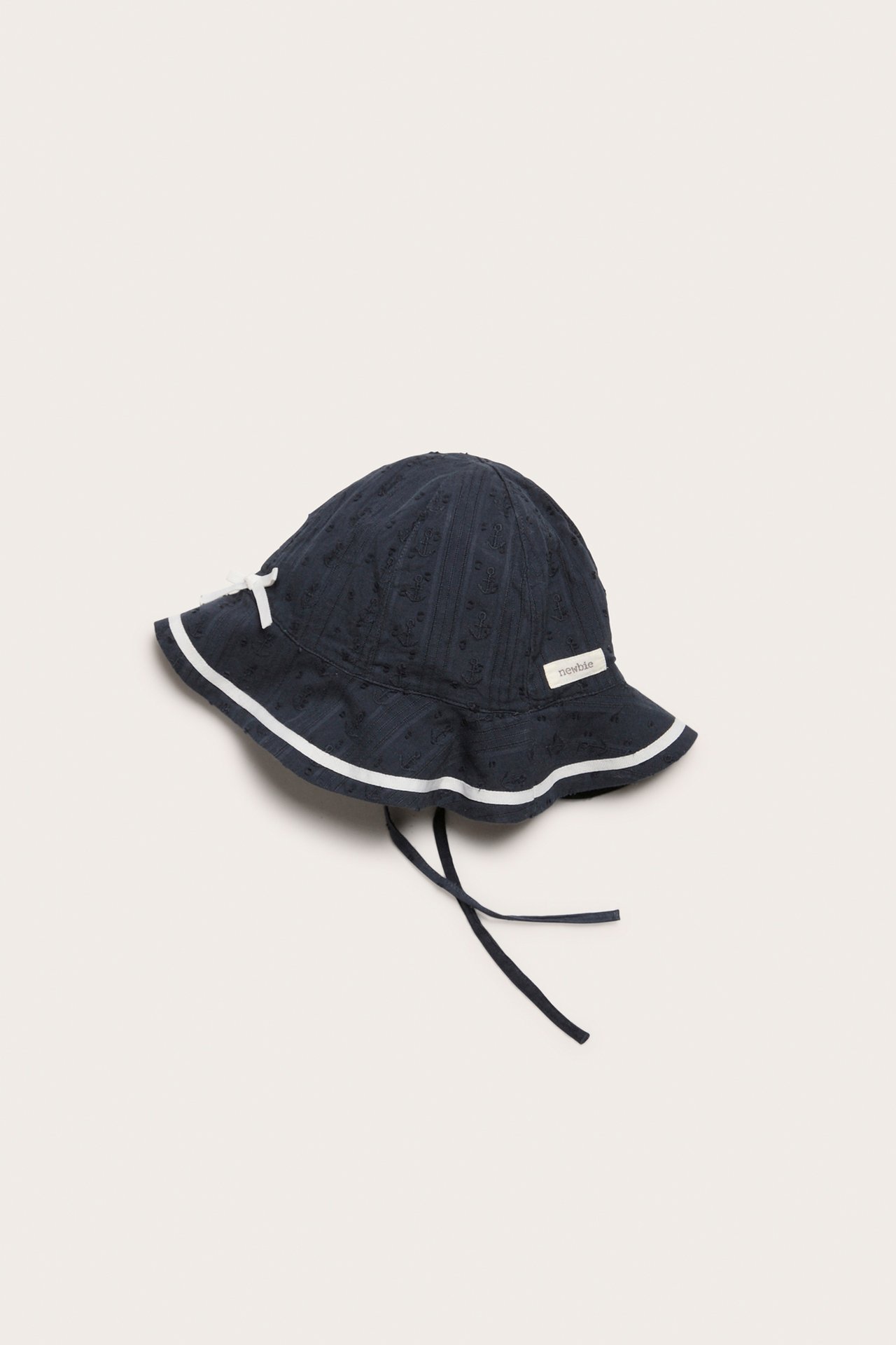 Front-side view: dark blue dobby sun hat with white brim stripes, small white bow, and tie-straps.