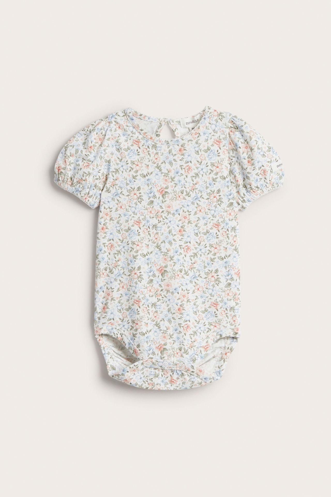 Vorderansicht: Off-white Baby-Body mit kleinem Blumenmuster, kurzen Puffärmeln und Druckknöpfen.