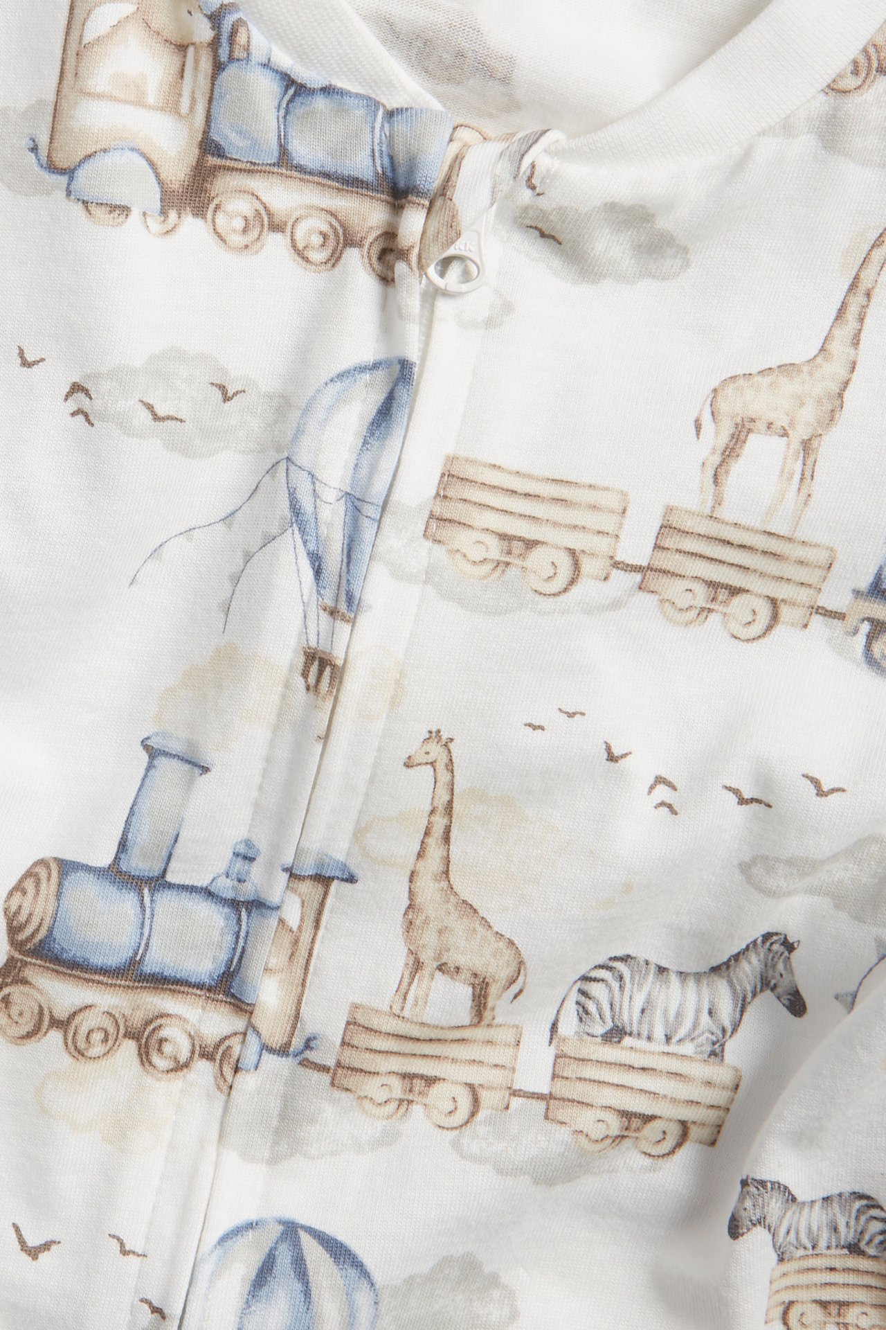 Close-up: Off-white baby romper in soft cotton jersey with vehicle and animal pattern, zip closure.