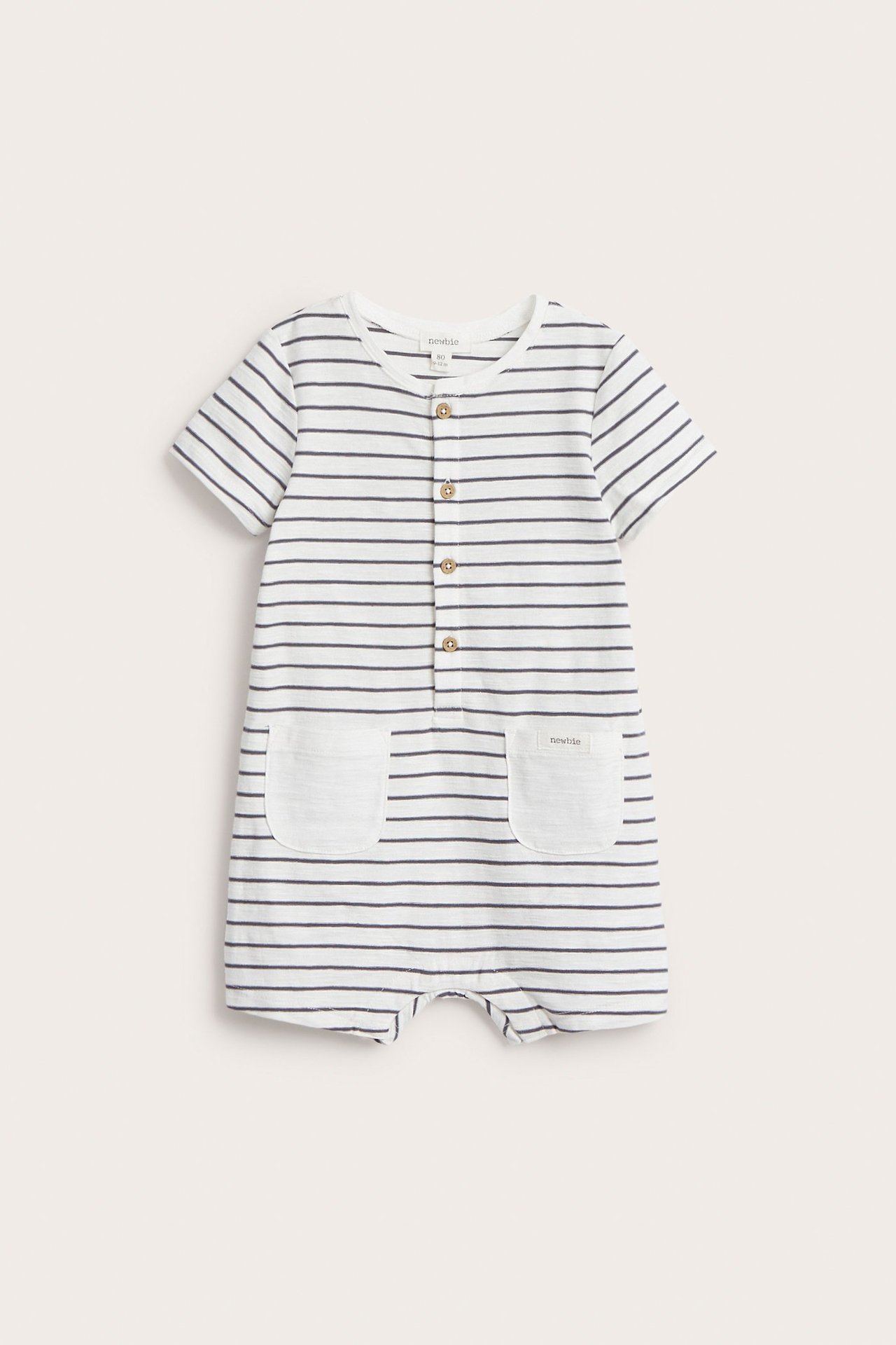 Front view of an off-white striped baby playsuit with short sleeves, front buttons, and two patch pockets.