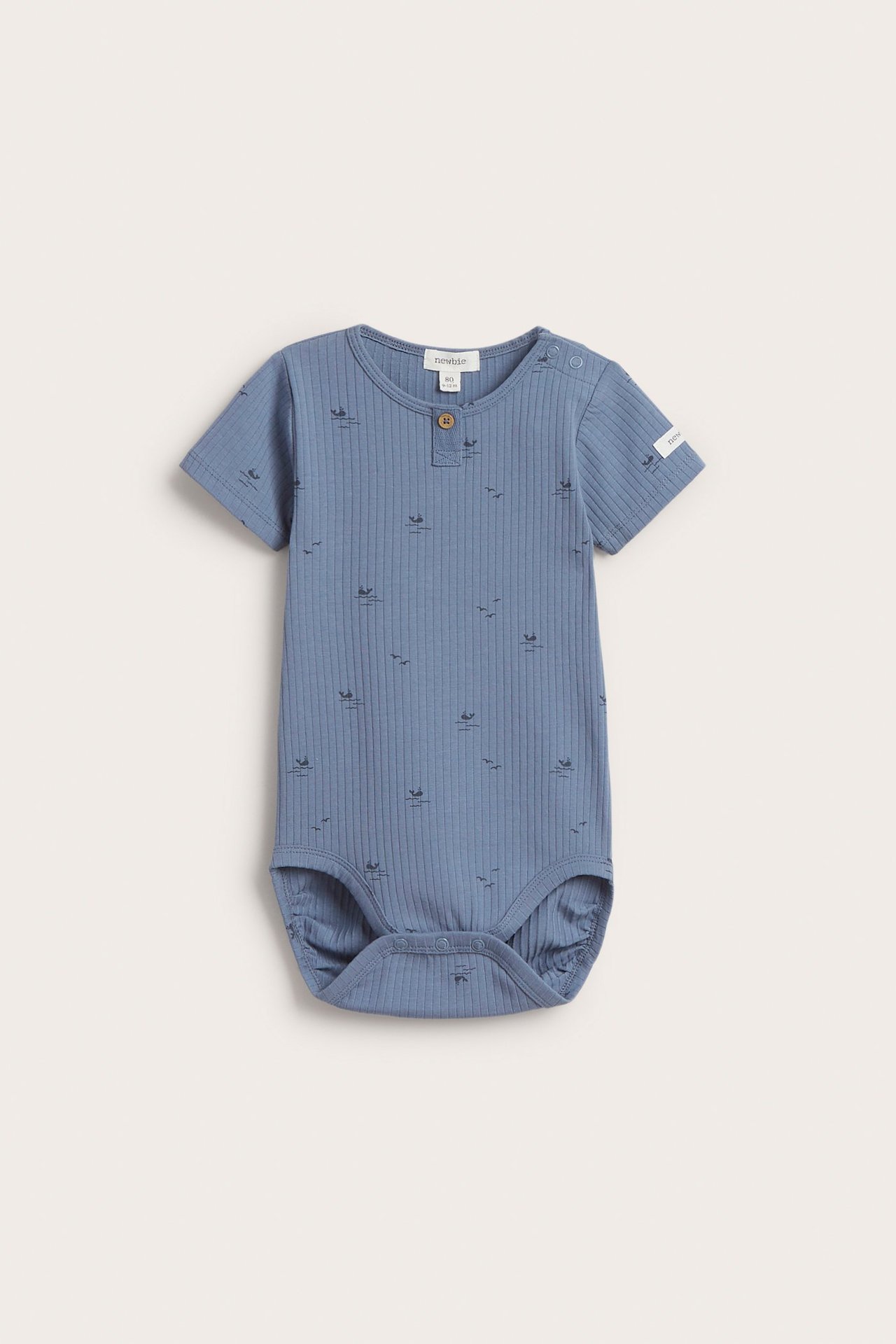 Front view of a baby's blue ribbed short-sleeved bodysuit with a whale and bird pattern, snap buttons.