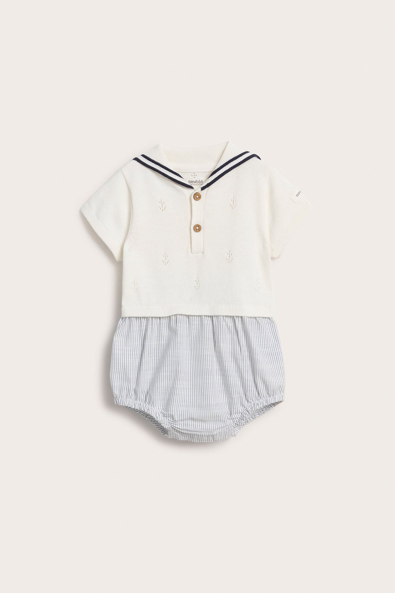 Vorderansicht: Off-white gestrickter Baby-Playsuit, Pointelle, gestreifter Matrosenkragen, Zierknöpfe, blau gestreifter Unterteil.