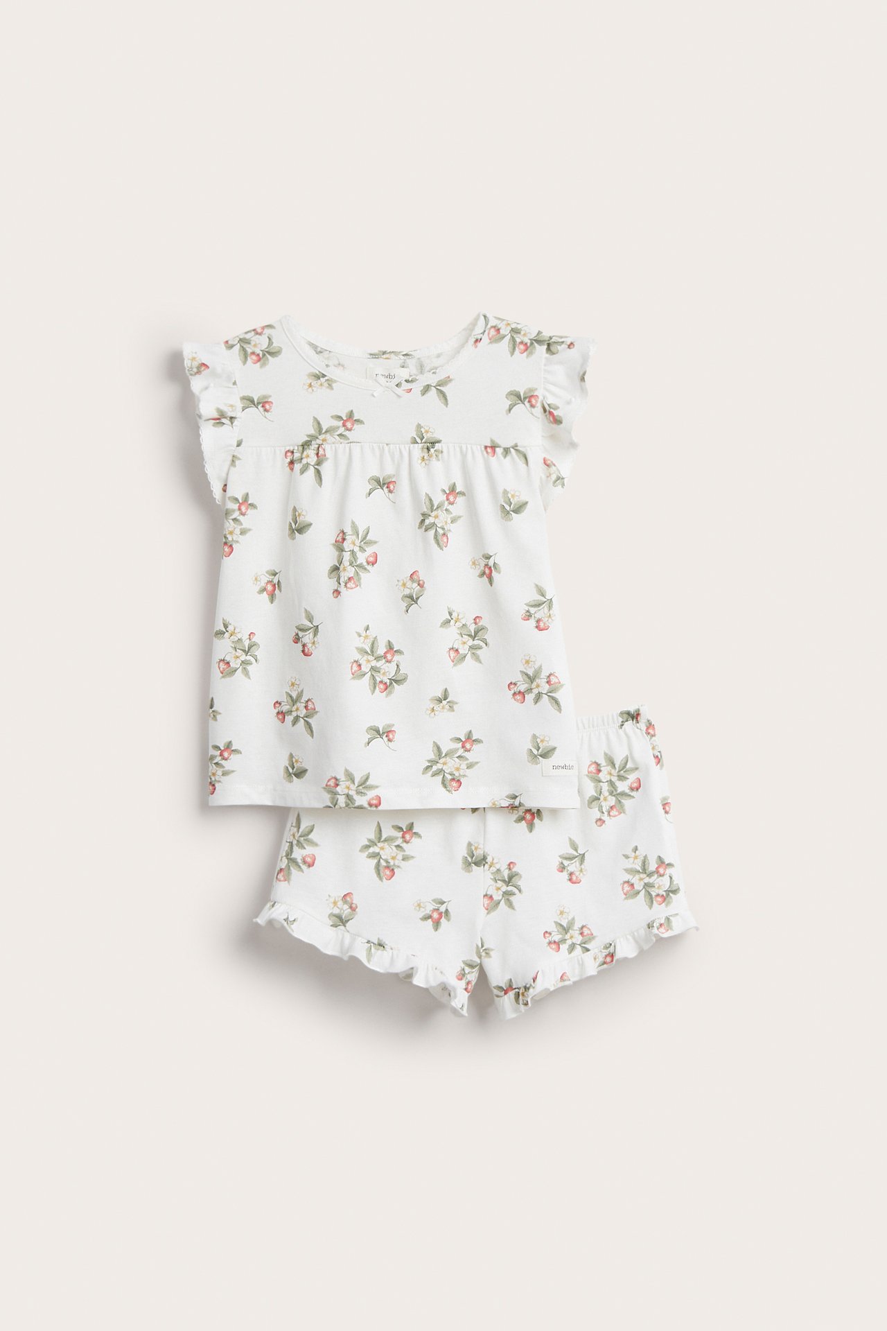 Vorderansicht eines cremefarbenen Kinder-Baumwollpyjama-Sets mit Erdbeermuster, Rüschenärmeln und passenden Shorts.