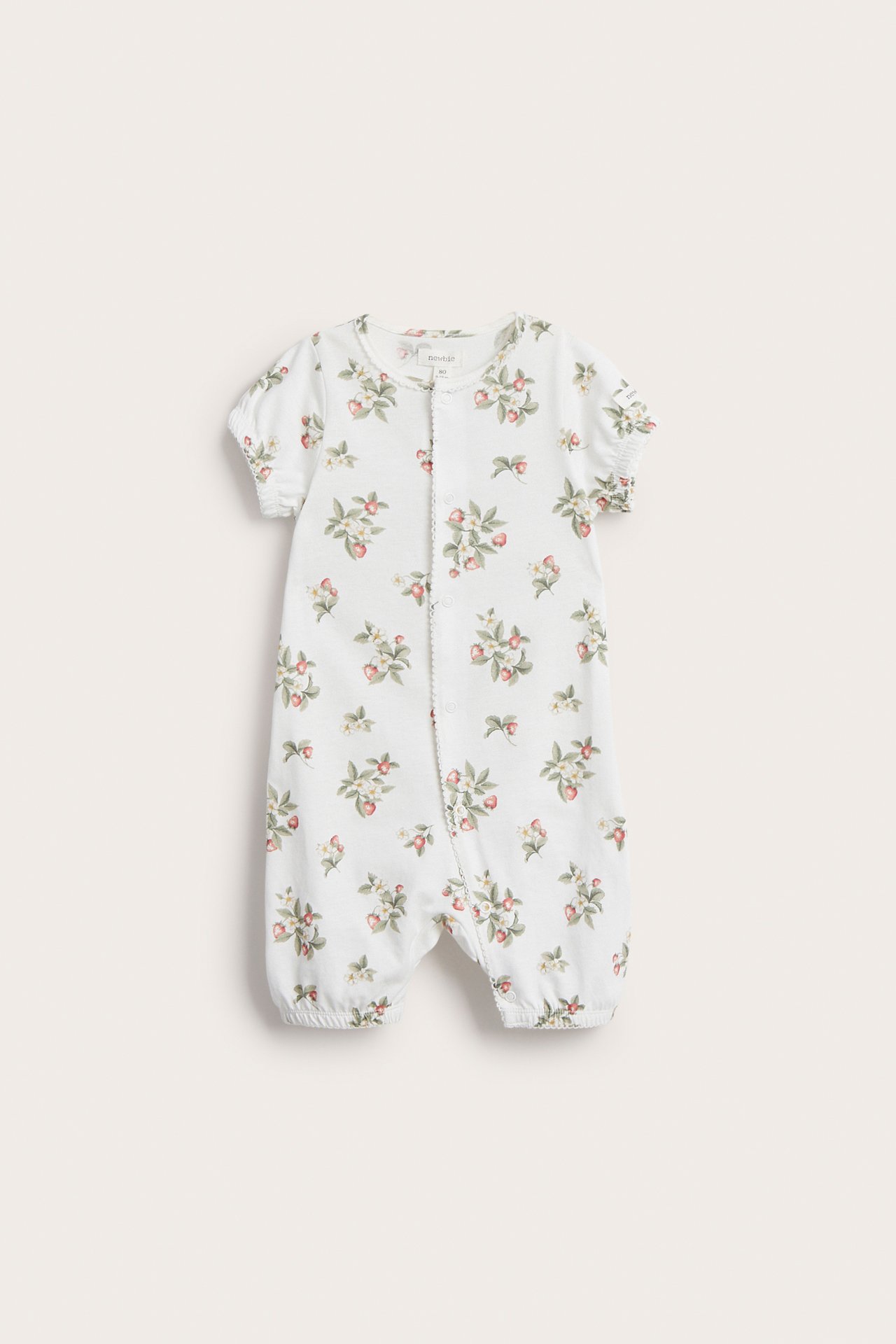 Vorderansicht: Off-white Baby-Baumwoll-Strampler mit kurzen Ärmeln, Beinen, Erdbeermuster, Druckknöpfen und Picot-Kanten.