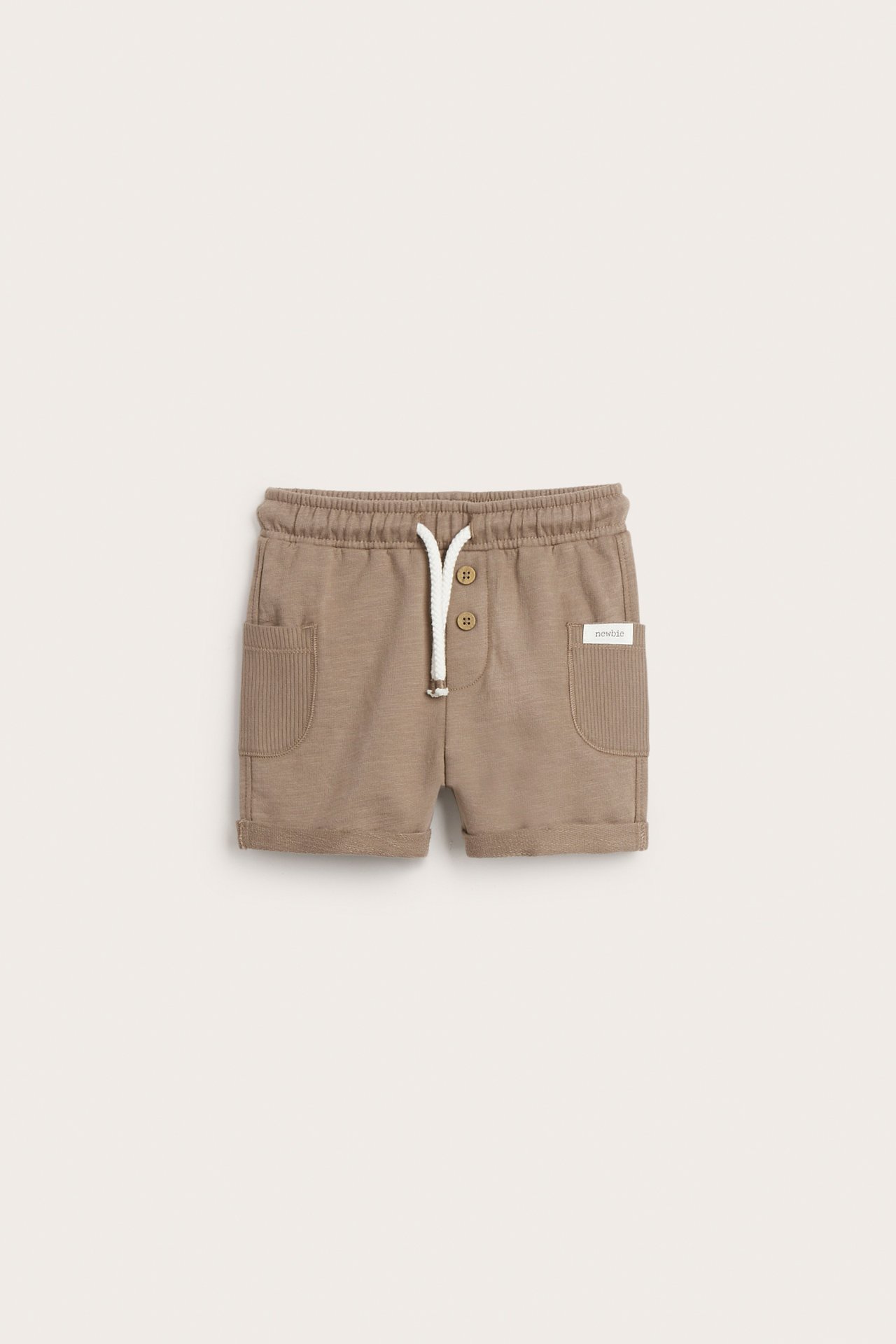 Front view of brown slub jersey baby shorts with elastic waist, white drawstring, decorative buttons, and ribbed pockets.