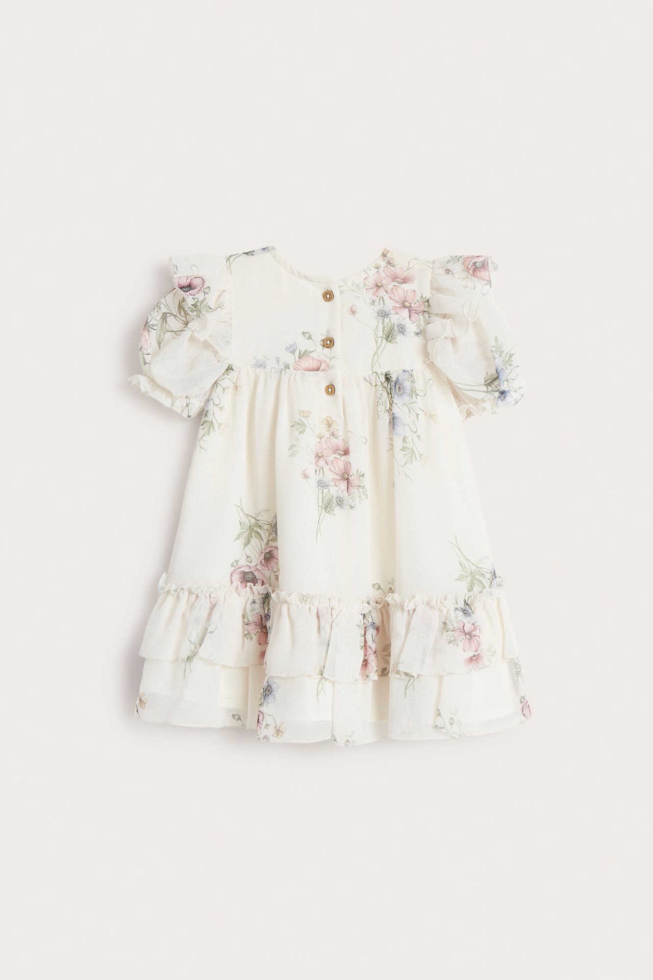 Front view of an off-white floral chiffon baby dress with puff sleeves, ruffles, and back buttons.