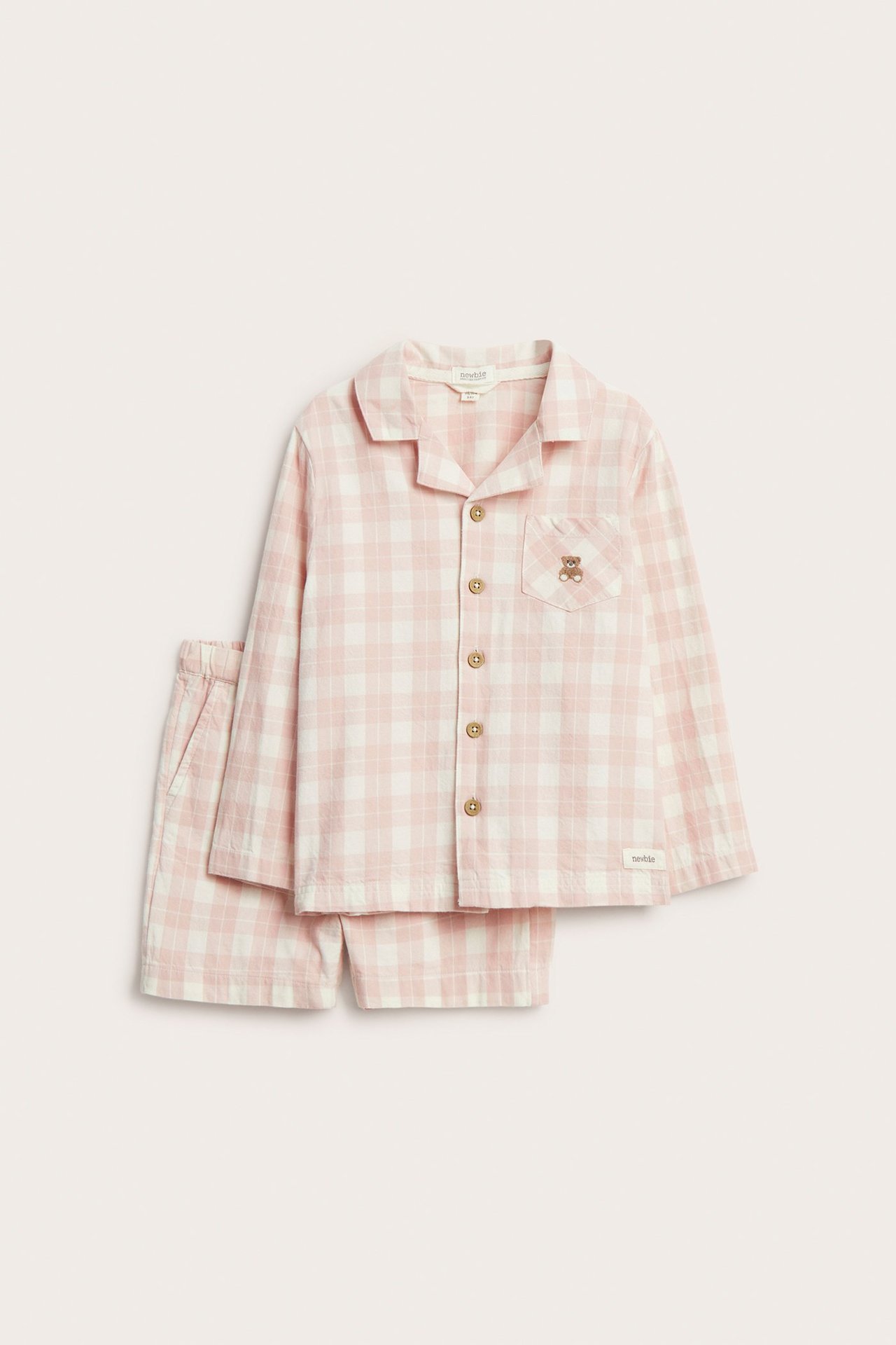 Front view: Kid's pink and white checked cotton pajama set. Long-sleeved shirt with teddy pocket and matching shorts.