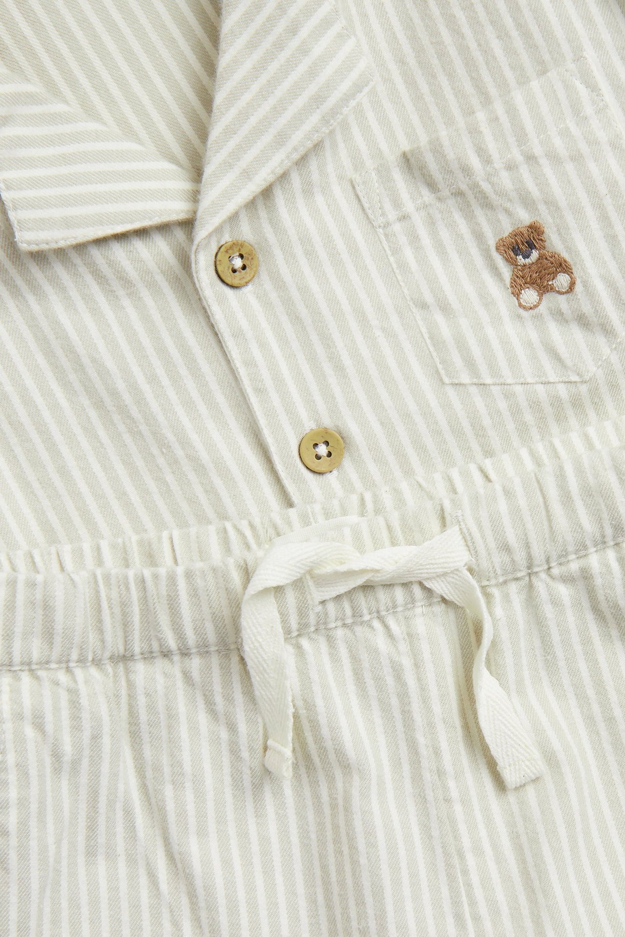 Close-up: Light green striped cotton pajama set with teddy bear embroidery, buttons, and drawstring.