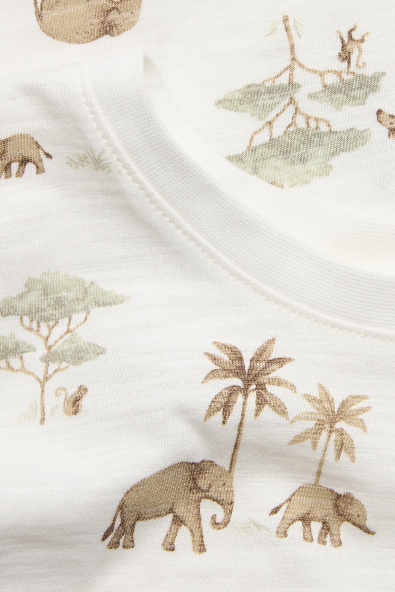 Close-up of a kid's off-white cotton t-shirt with an animal and tree pattern, ribbed neckline.