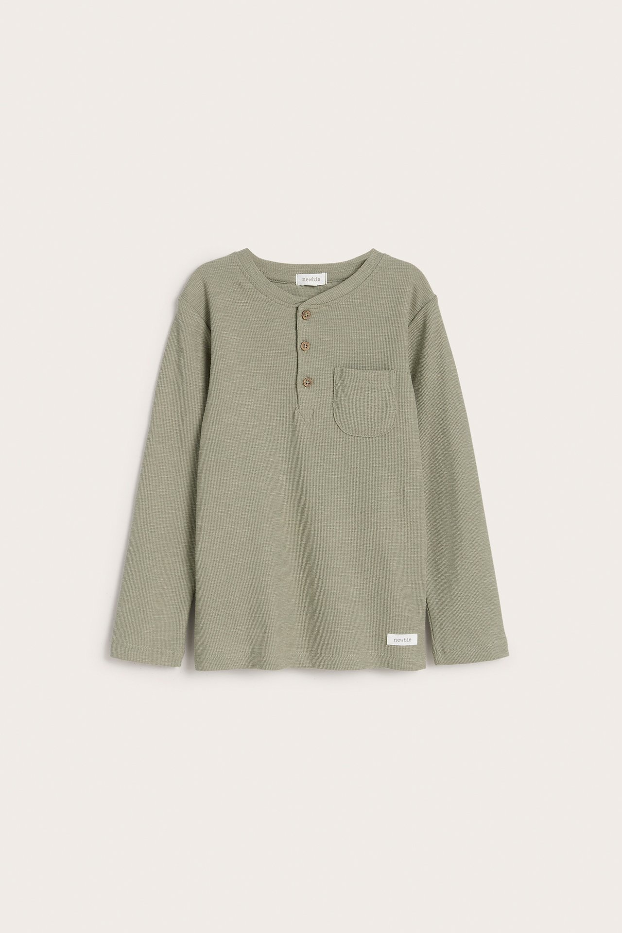 Front view of a kid's dark green long-sleeved henley shirt in waffle knit with three buttons and a chest pocket.