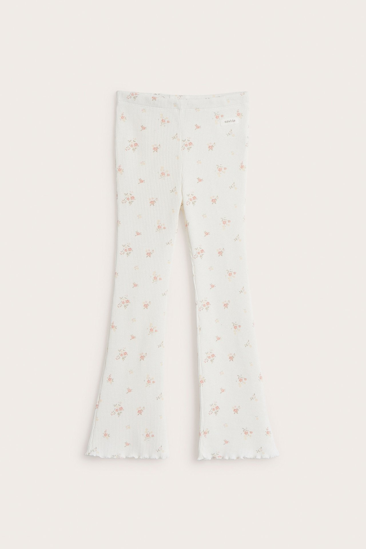 Front view of off-white baby waffle pants with a floral print and flared, ruffled hems.