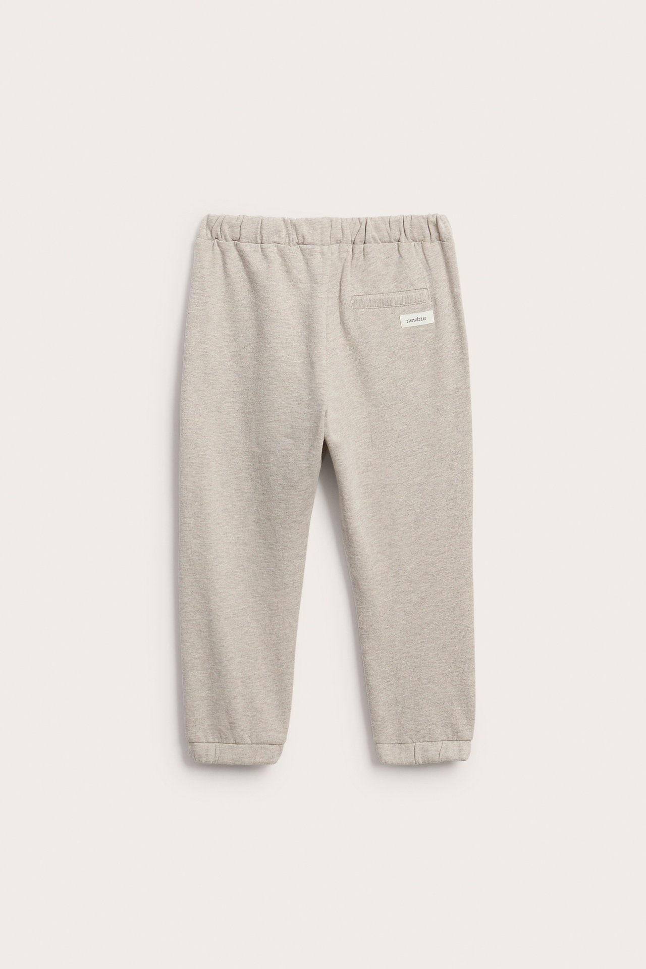 Back view of light grey joggers with elastic waistband, ribbed cuffs, and a small back label.
