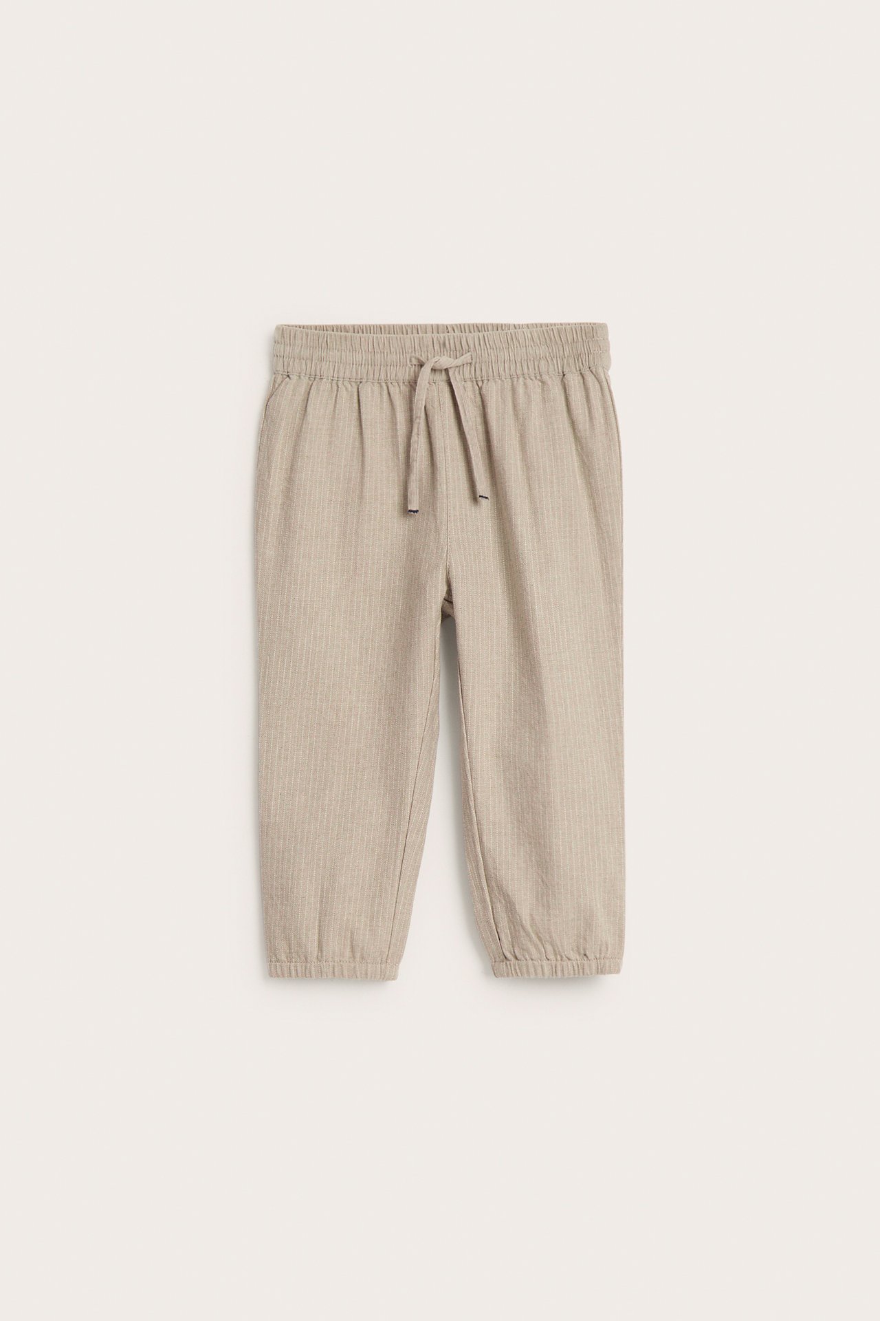 Front view of kid's beige melange striped woven pants with an elastic waist, drawstring, and elastic cuffs.