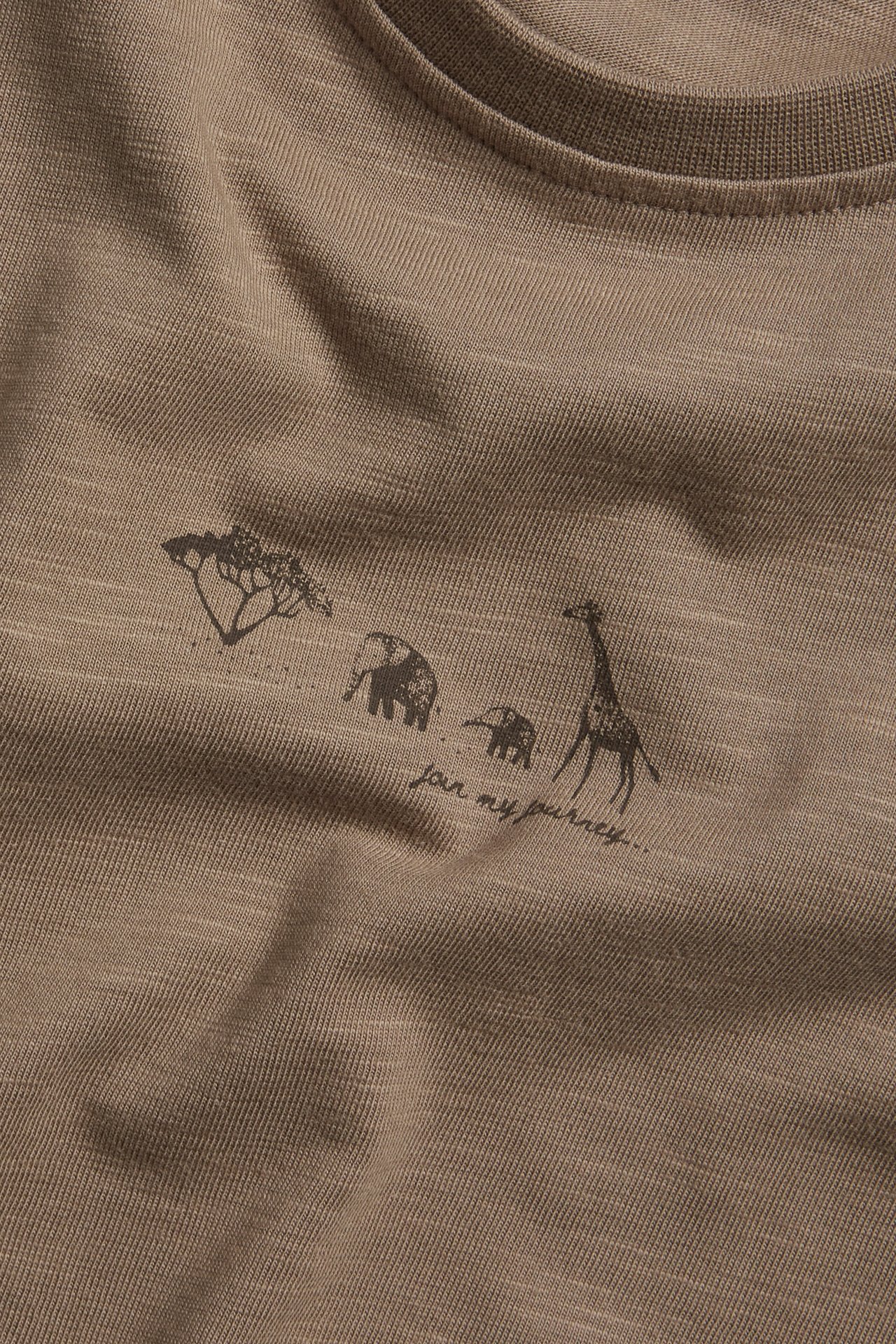 Nahaufnahme eines braunen Slub-Jersey-T-Shirts mit dunklem Tier- und Textdruck.
