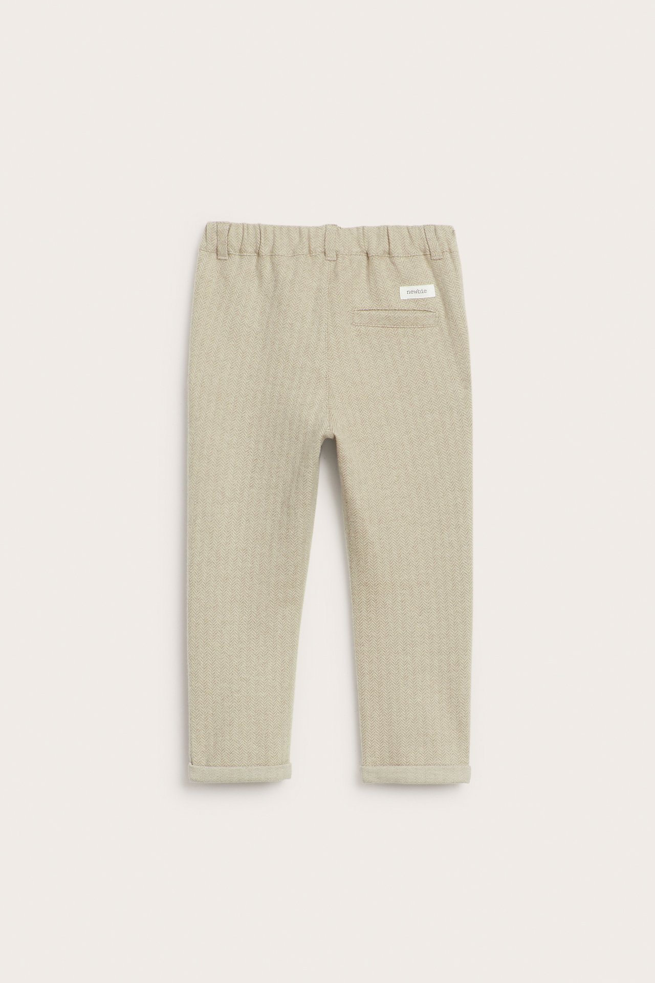 Rückansicht: Kinderhose in Beige-Melange mit Fischgrätmuster, elastischem Bund, Ziertasche, umgekrempelten Säumen.