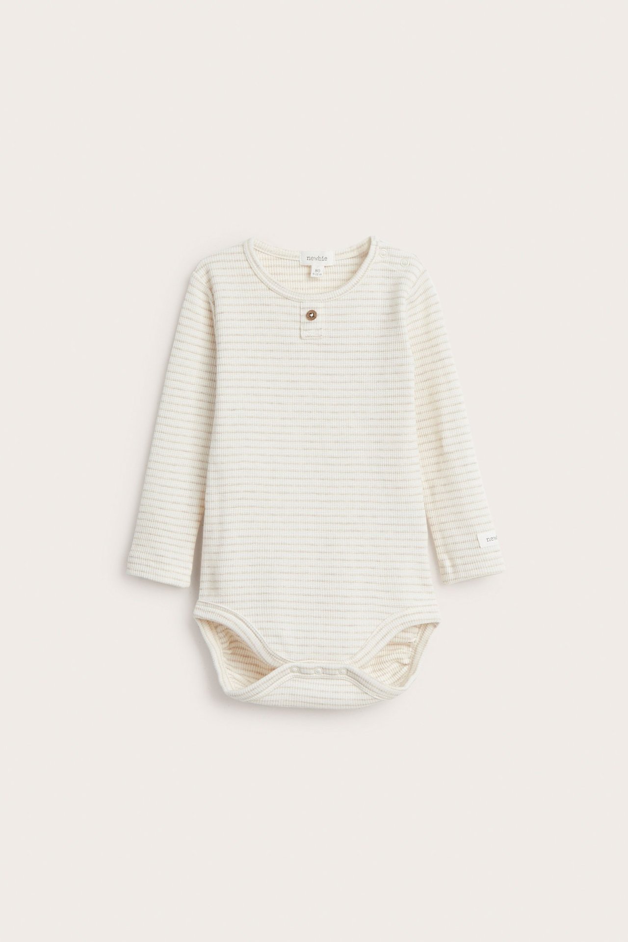 Front view of a baby's long-sleeved beige melange striped waffle bodysuit with snap buttons.