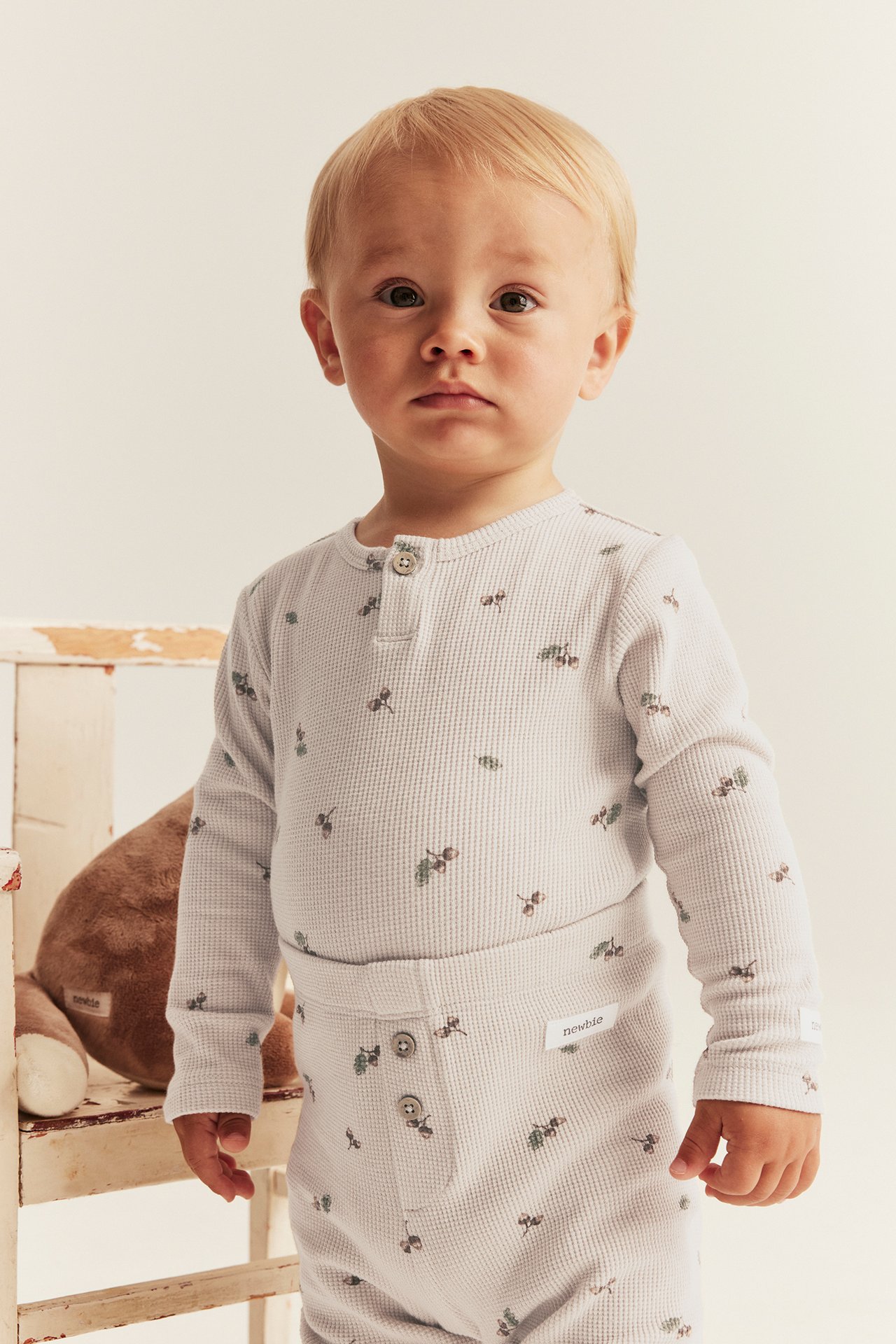 Front view of a baby wearing a light beige waffle-knit long-sleeved body with acorn print and matching pants.