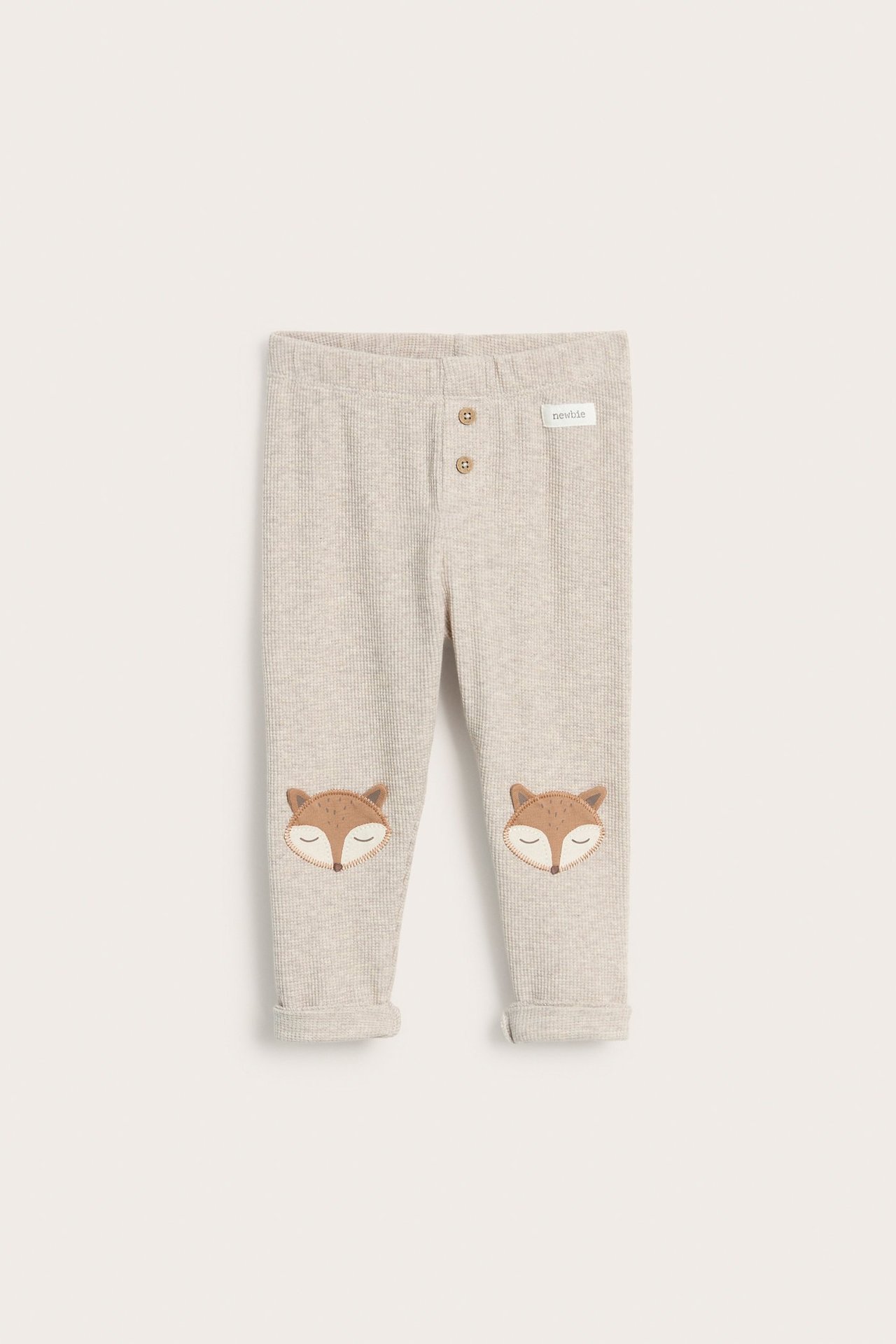 Vorderansicht beigefarbener Waffel-Baby-Leggings mit Fuchs-Applikationen an den Knien und Zierknöpfen.