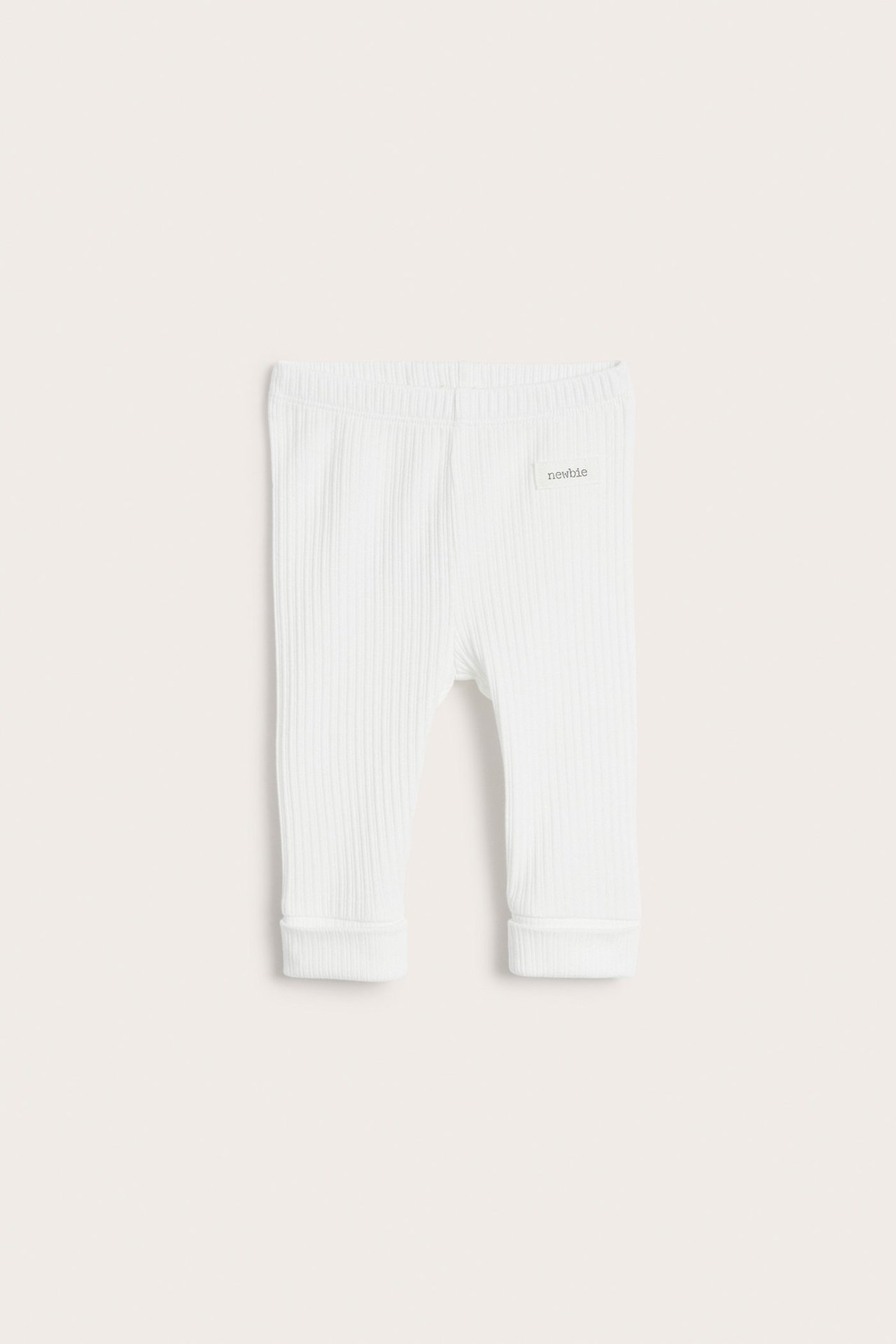 Front view of off-white ribbed baby leggings with an elastic waist and folded cuffs.