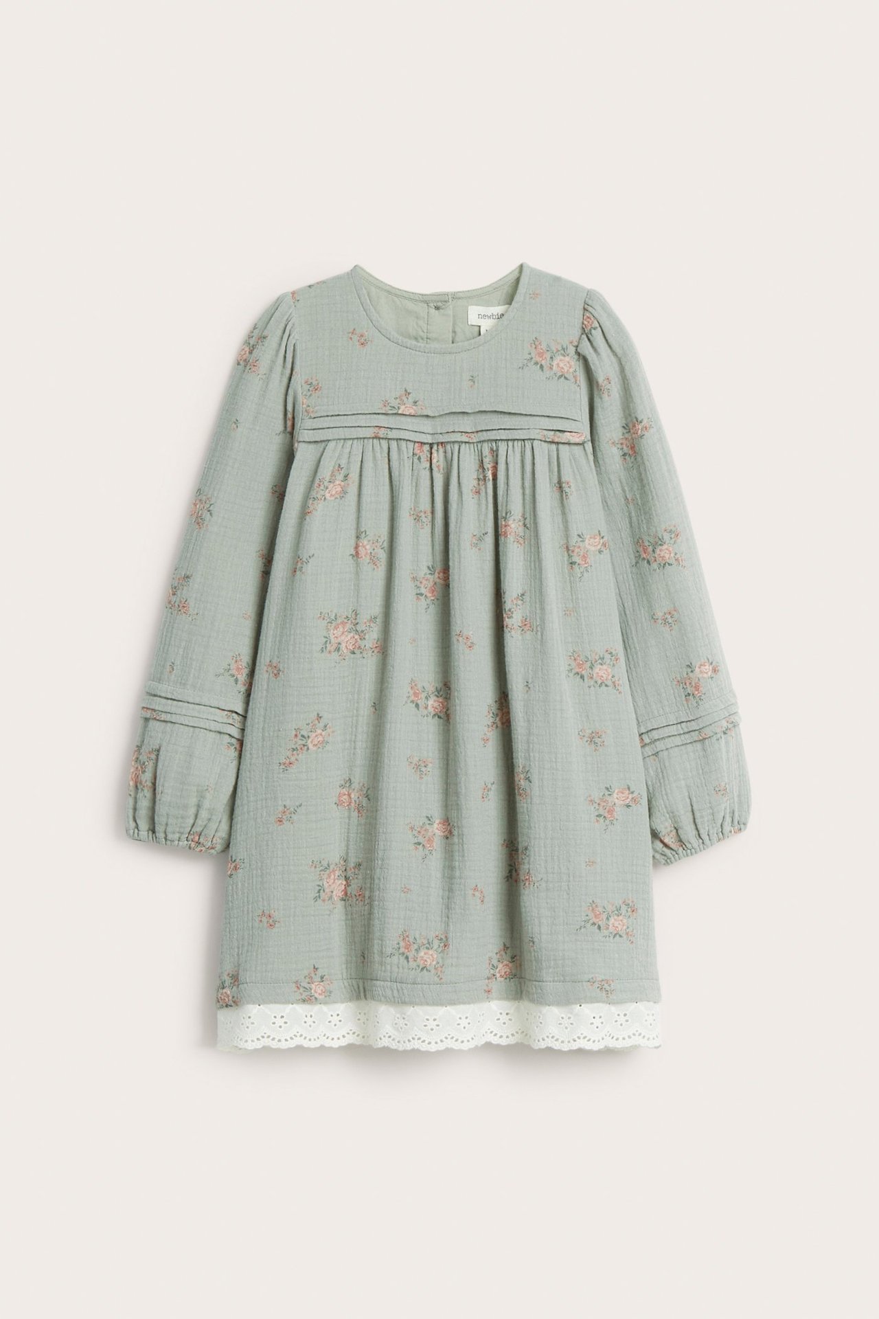 Front view of a kid's light green floral cotton dress with pintucks and white lace hem.