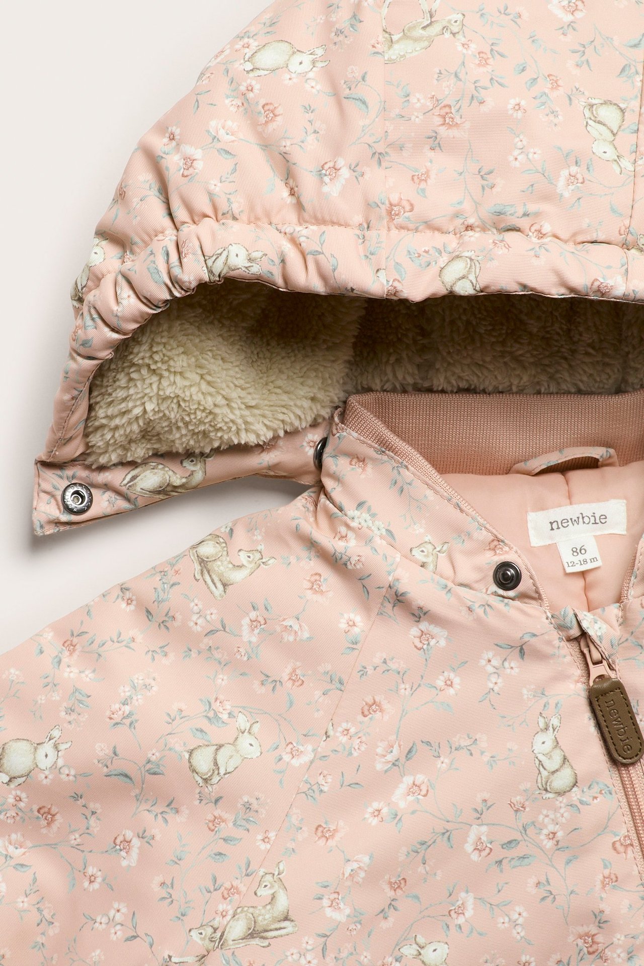 Nahaufnahme: Rosa wattierter Baby-Overall mit Blumen- und Tiermuster, pilegefütterter Kapuze, Frontreißverschluss.
