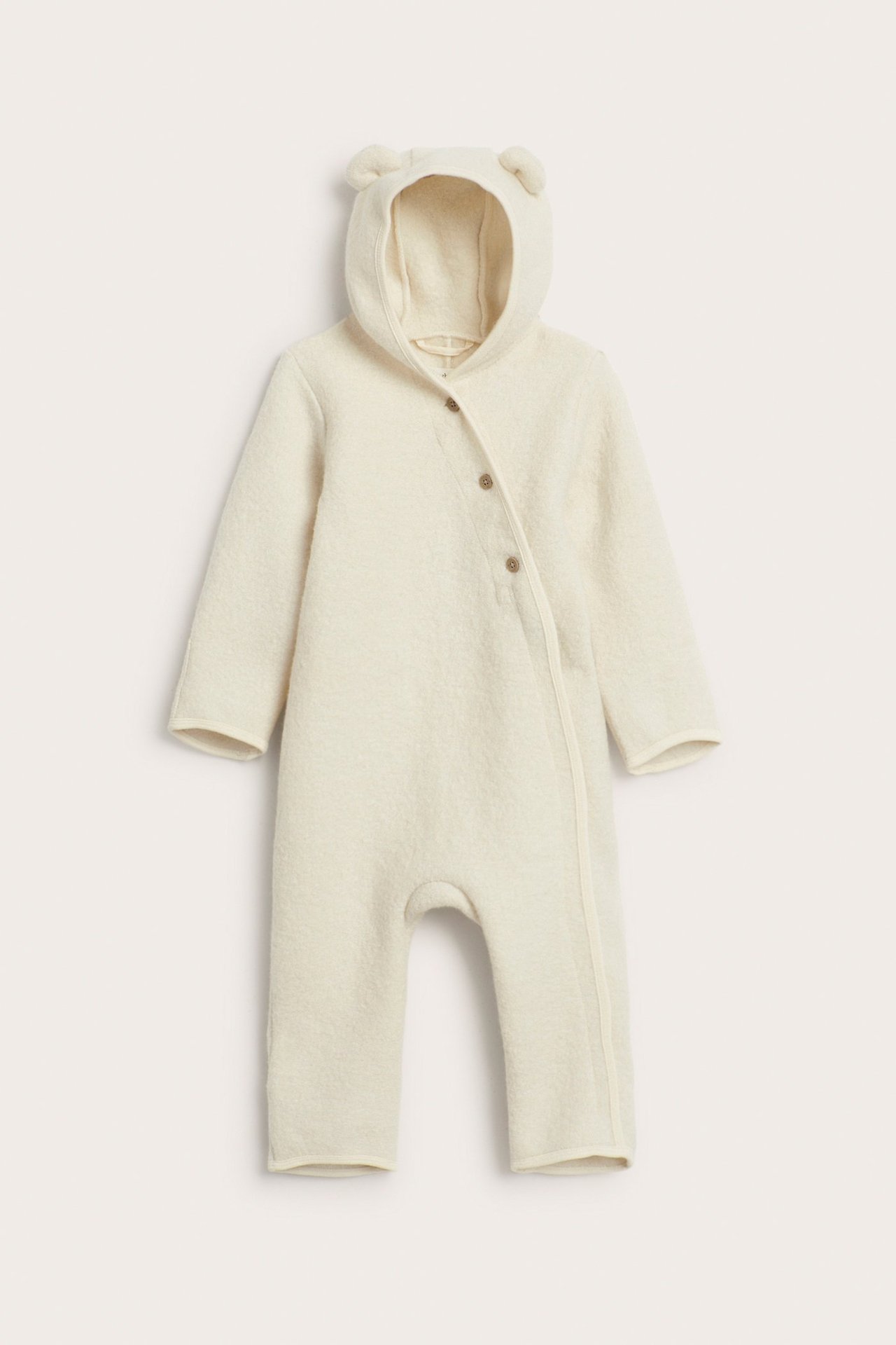 Front view of a light beige wool baby overall with a hooded design, decorative ears, and front buttons.