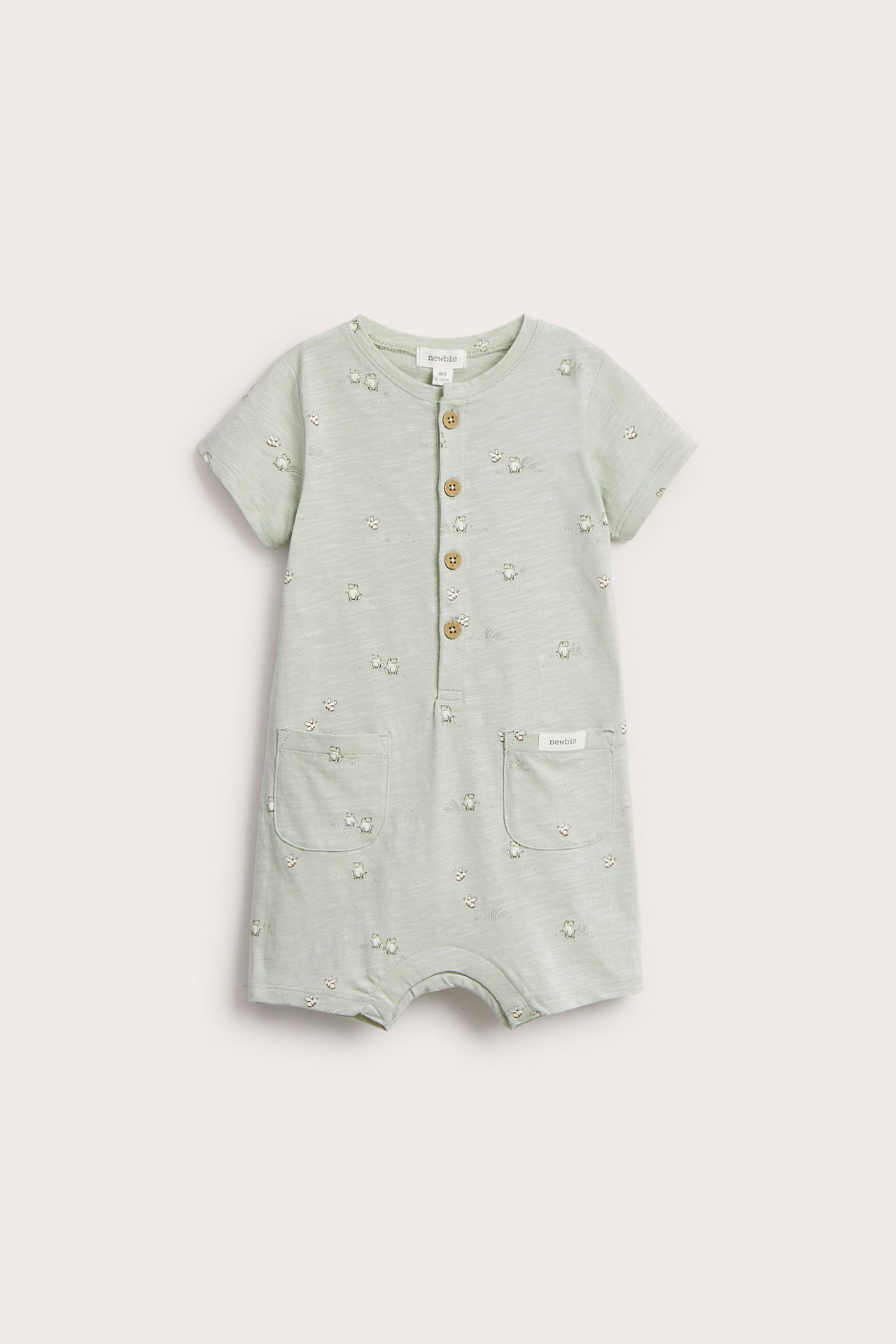 Front view: Baby's light green cotton slub playsuit with animal print, front buttons, and two pockets.