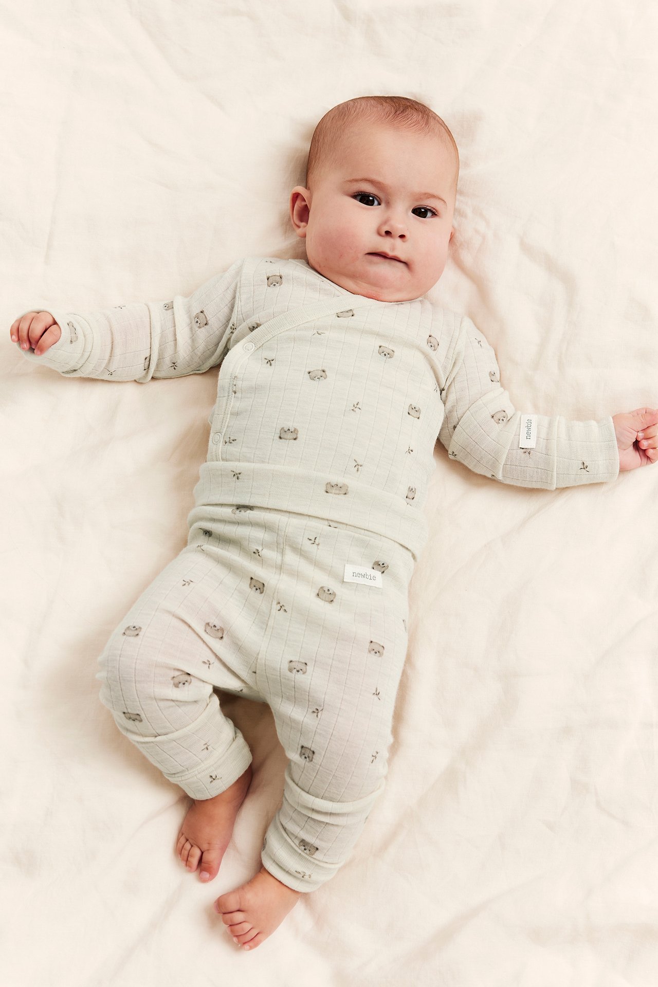 Front view of baby wearing a light green ribbed two-piece outfit with bear print.